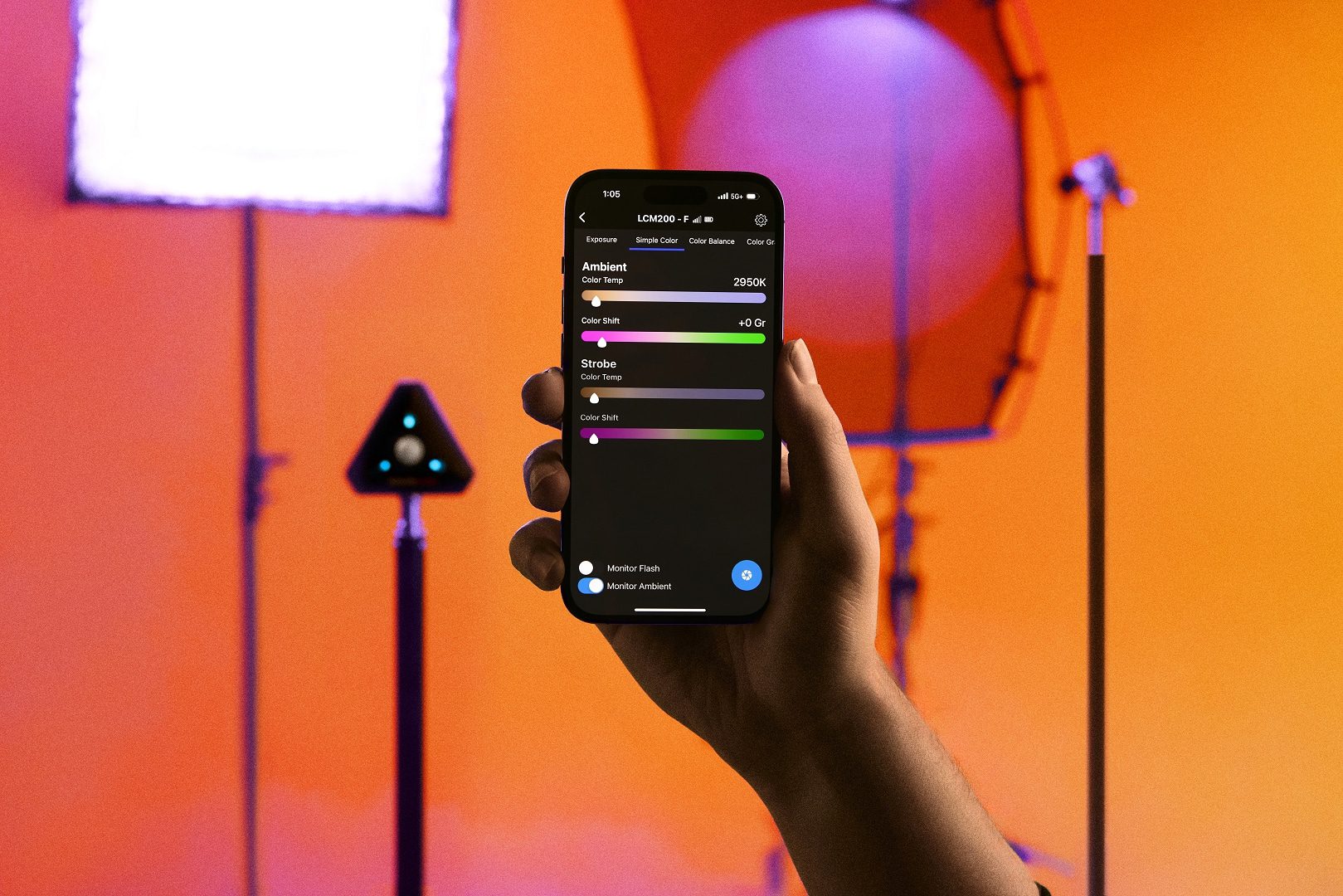 a hand holding a smartphone displaying settings for lighting control with colorful background lighting and studio equipment in the frame digital production A hand holding a smartphone displaying settings for lighting control, with colorful background lighting and studio equipment in the frame.