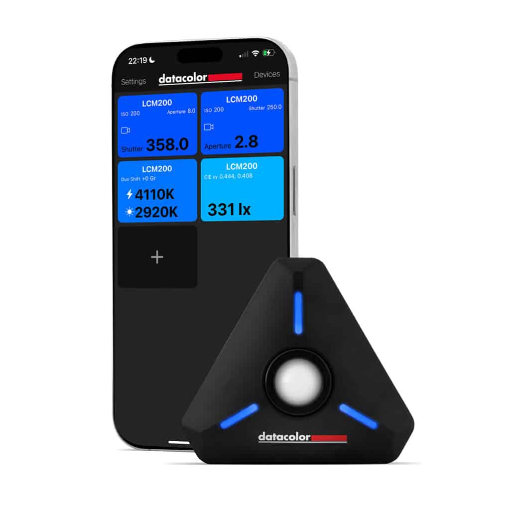 a smartphone displaying a color calibration app with measurement data next to a black triangular colorimeter with blue led accents from datacolor digital production A smartphone displaying a color calibration app with measurement data next to a black triangular colorimeter with blue LED accents from Datacolor.