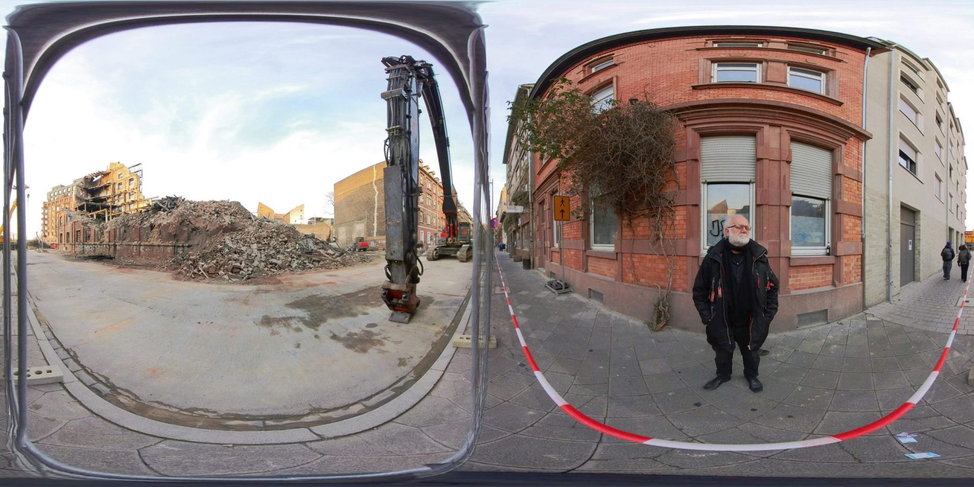 a panoramic view showing a construction site on the left with a pile of debris and a construction crane on the right a man stands near a brick building with ivy on its wall while two other people walk on the sidewalk digital production A panoramic view showing a construction site on the left with a pile of debris and a construction crane. On the right, a man stands near a brick building with ivy on its wall, while two other people walk on the sidewalk.