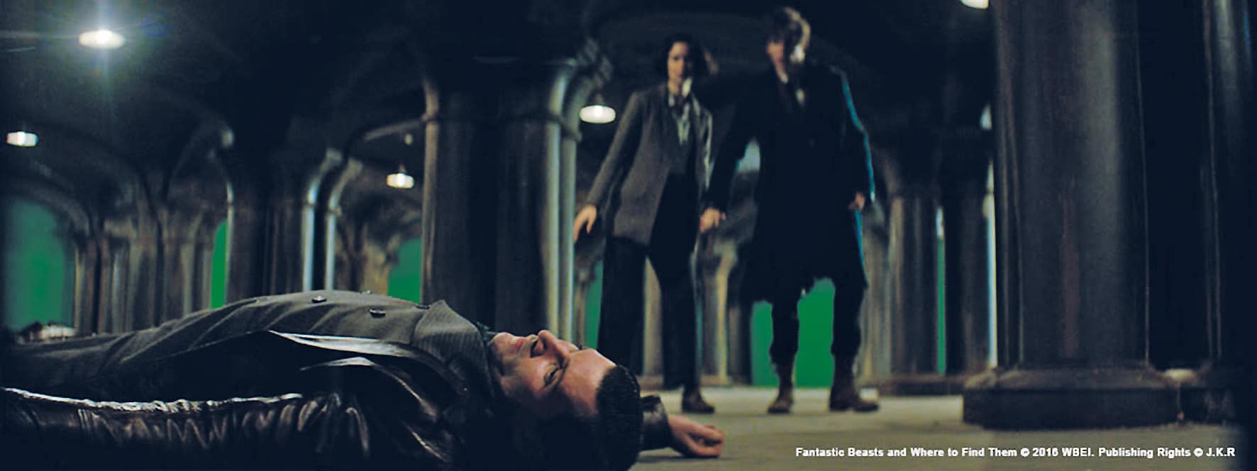 a scene featuring two characters standing near a person lying on the ground in a dimly lit underground setting with visible green screen elements in the background digital production A scene featuring two characters standing near a person lying on the ground in a dimly lit underground setting, with visible green screen elements in the background.