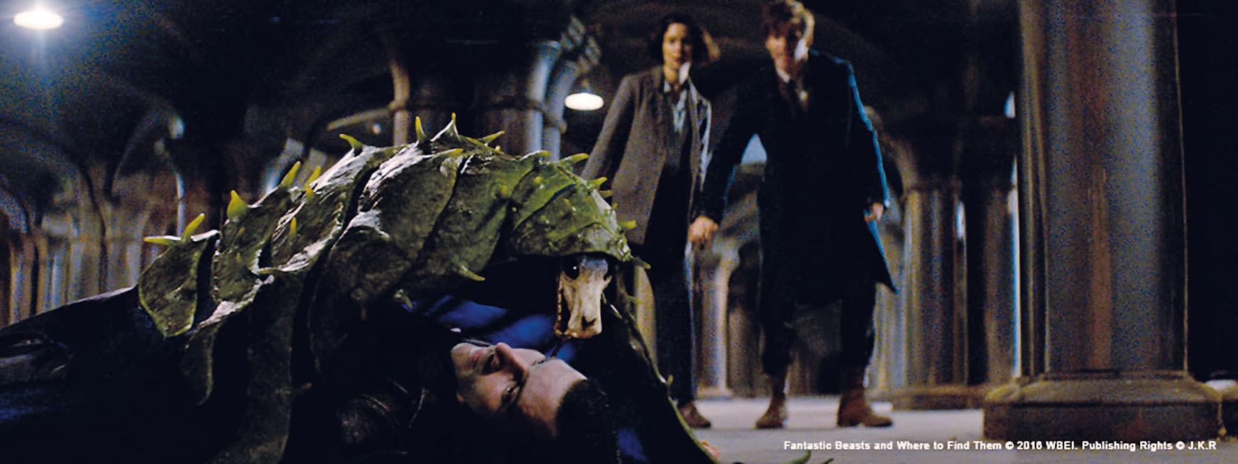 a creature resembling a large reptile is lying on the floor while two men in formal attire observe from behind the setting appears to be an underground space with arched columns digital production A creature resembling a large reptile is lying on the floor, while two men in formal attire observe from behind. The setting appears to be an underground space with arched columns.