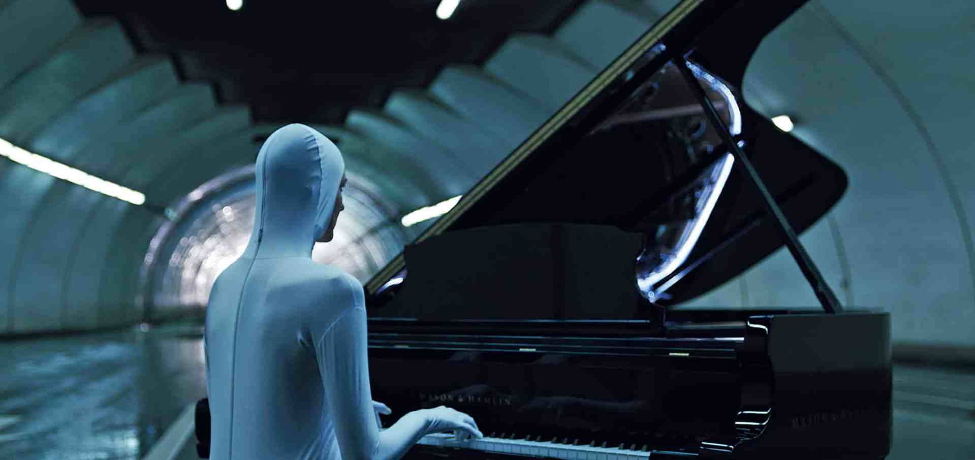 a figure in a skintight white outfit playing a grand piano in a modern dimly lit tunnel the piano has a reflective surface and the surrounding walls curve in a futuristic manner digital production A figure in a skin-tight white outfit playing a grand piano in a modern, dimly lit tunnel. The piano has a reflective surface, and the surrounding walls curve in a futuristic manner.