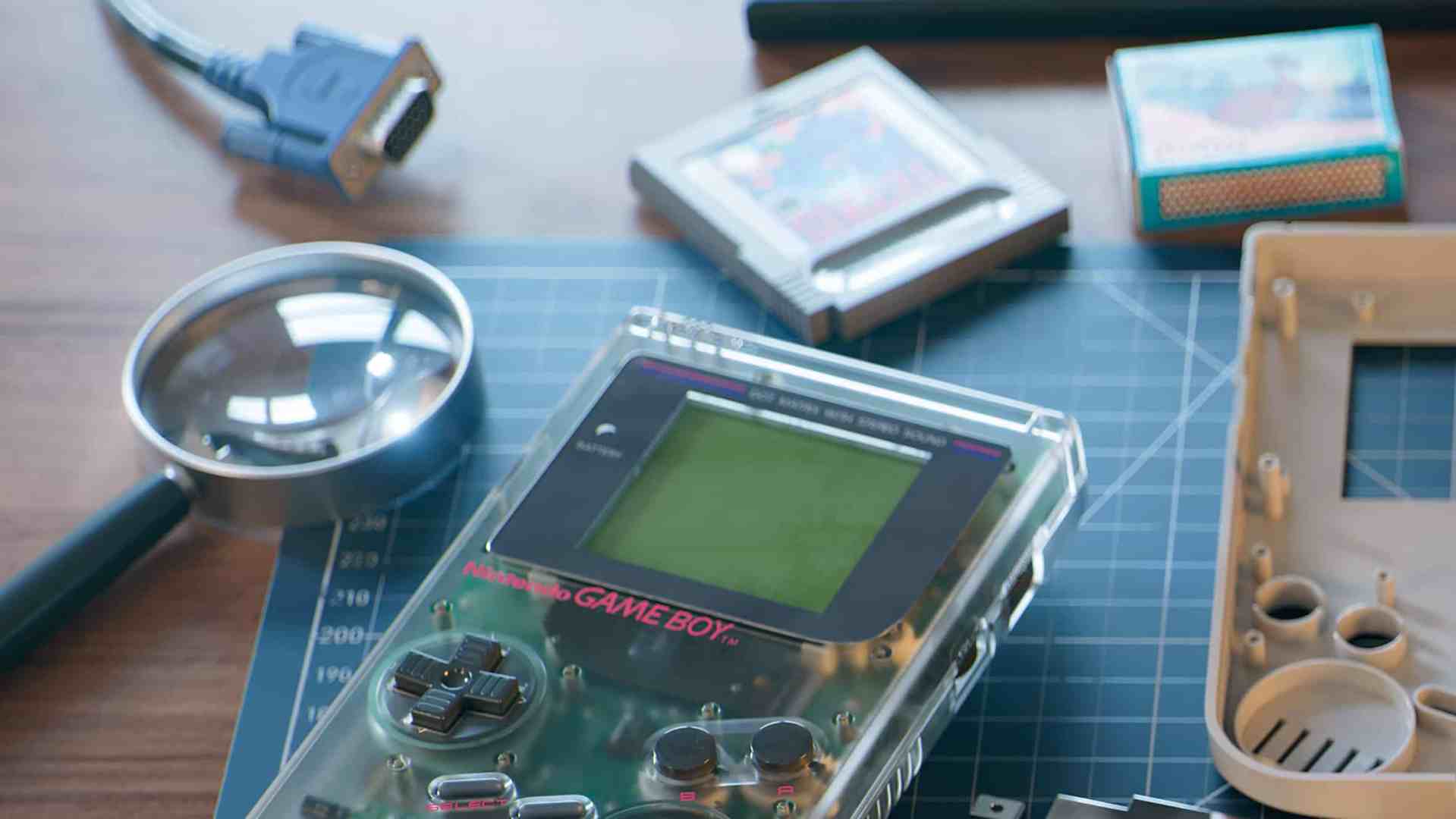 a transparent vintage game boy console surrounded by a magnifying glass a blue cable and game cartridges displayed on a cutting mat with measurement markings digital production A transparent vintage Game Boy console surrounded by a magnifying glass, a blue cable, and game cartridges displayed on a cutting mat with measurement markings.