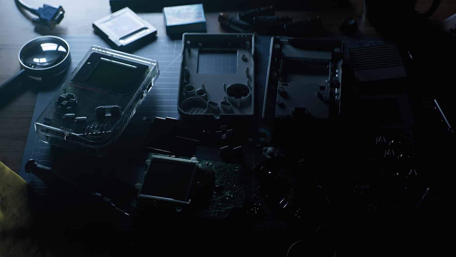 a collection of disassembled electronic components and devices including a handheld gaming console and various tools arranged on a dark work surface a magnifying glass is positioned nearby digital production A collection of disassembled electronic components and devices, including a handheld gaming console and various tools, arranged on a dark work surface. A magnifying glass is positioned nearby.