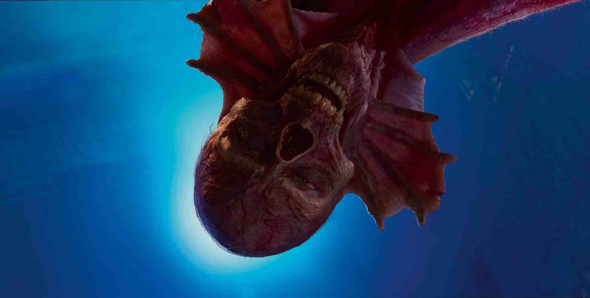 a closeup of a fictional creature with a skeletal face and elongated fins viewed against a blue background the creature appears to be floating or hanging upside down showcasing its unusual features digital production A close-up of a fictional creature with a skeletal face and elongated fins, viewed against a blue background. The creature appears to be floating or hanging upside down, showcasing its unusual features.