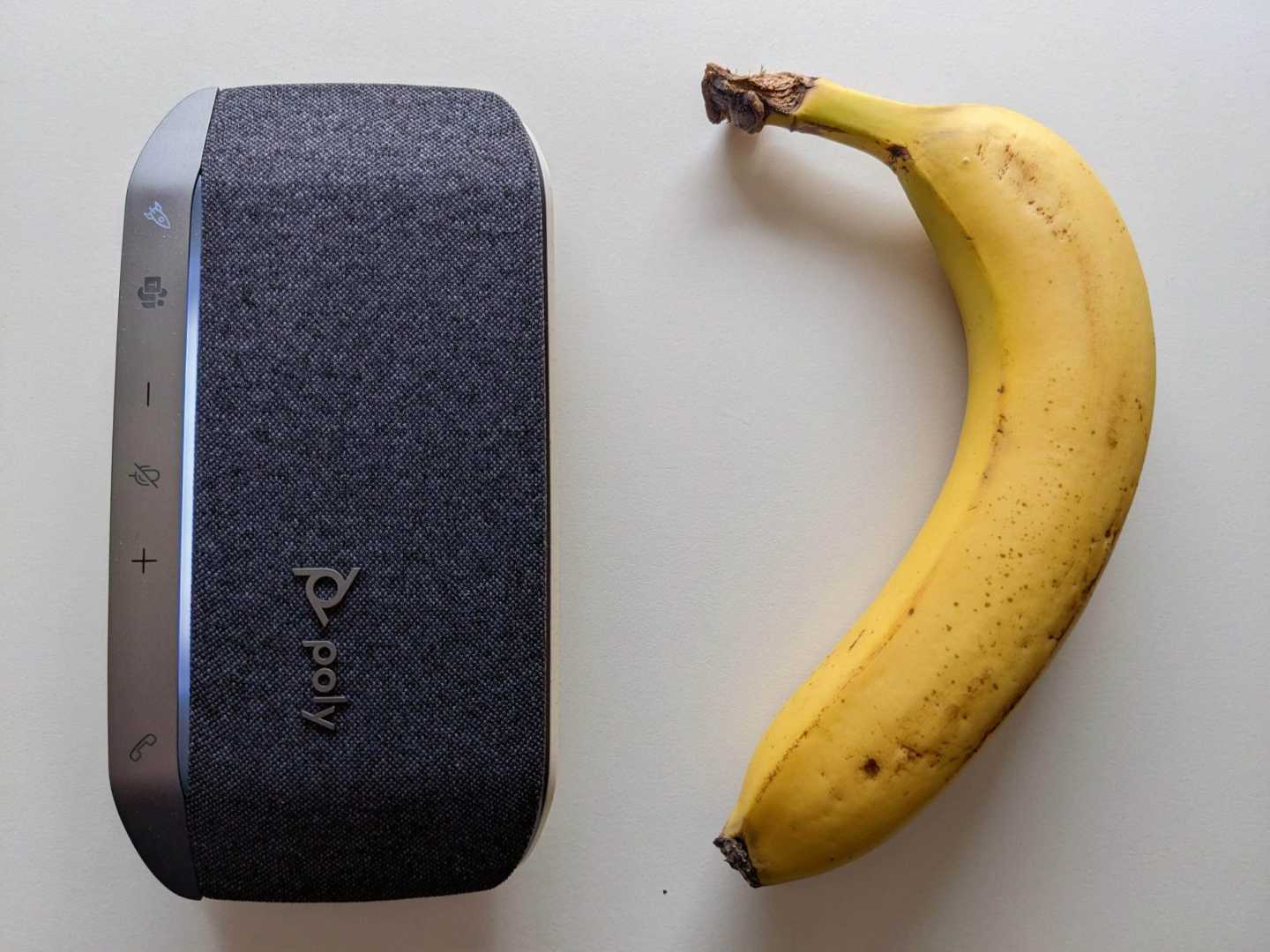 a portable speaker next to a banana digital production A portable speaker next to a banana.
