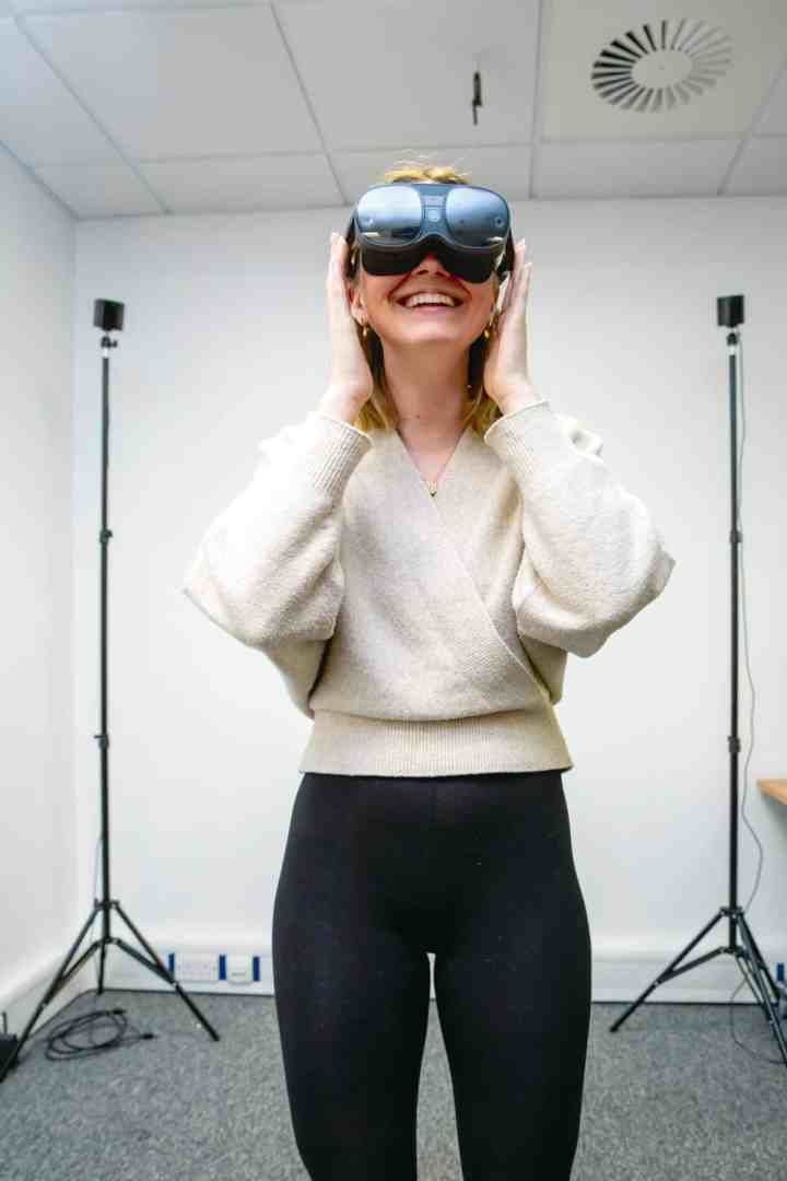 a woman wearing vr headset smiling indoors digital production A woman wearing VR headset, smiling indoors.