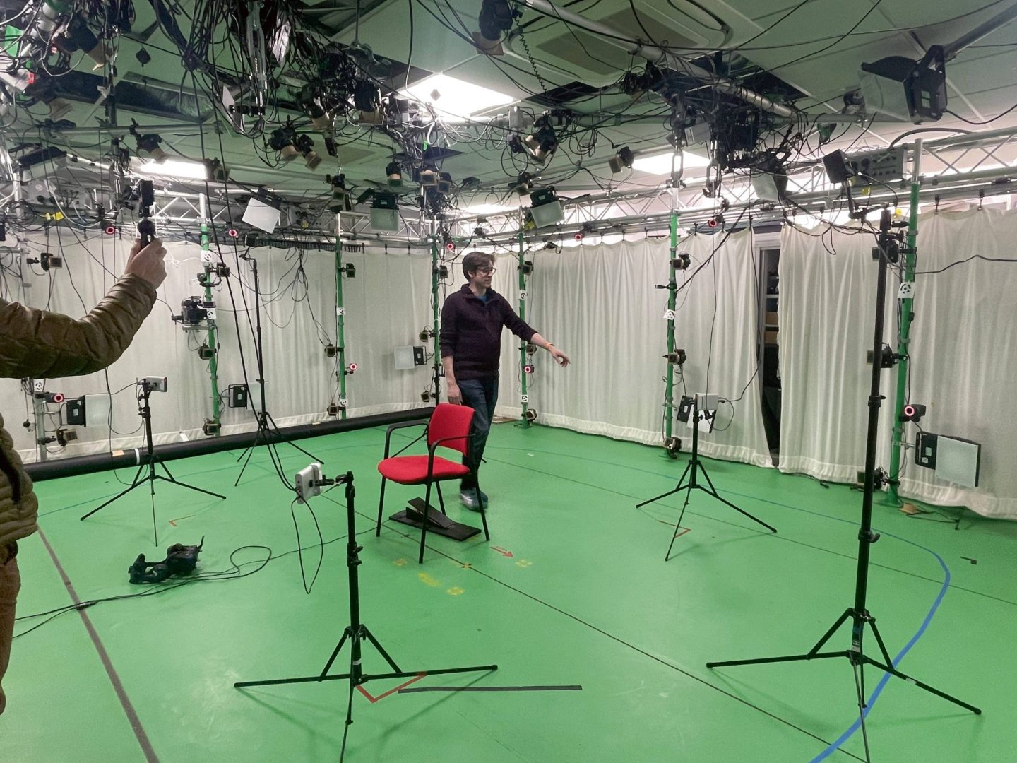 a person gesturing in a motion capture studio filled with cameras and equipment digital production A person gesturing in a motion capture studio filled with cameras and equipment.