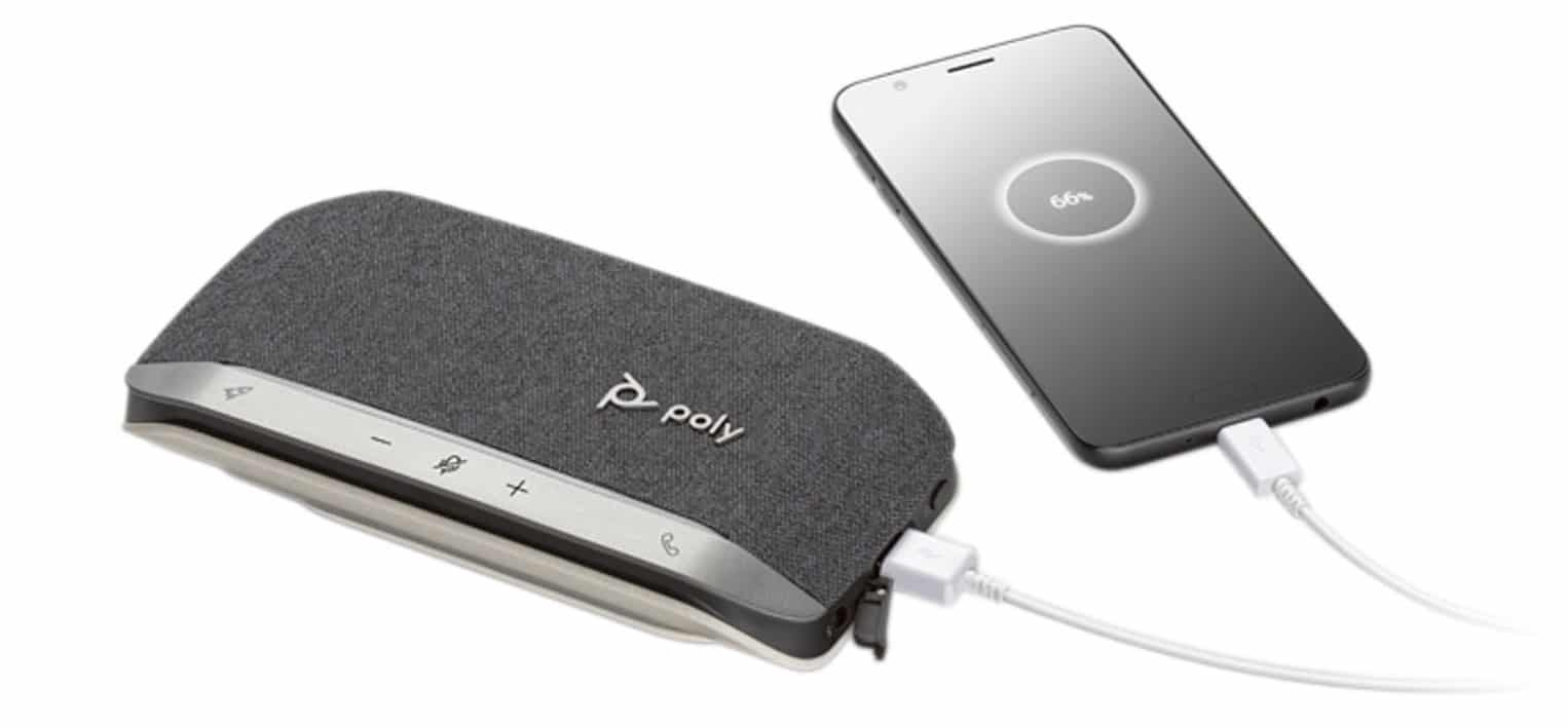a portable speakerphone next to a smartphone with a charging cable digital production A portable speakerphone next to a smartphone with a charging cable.
