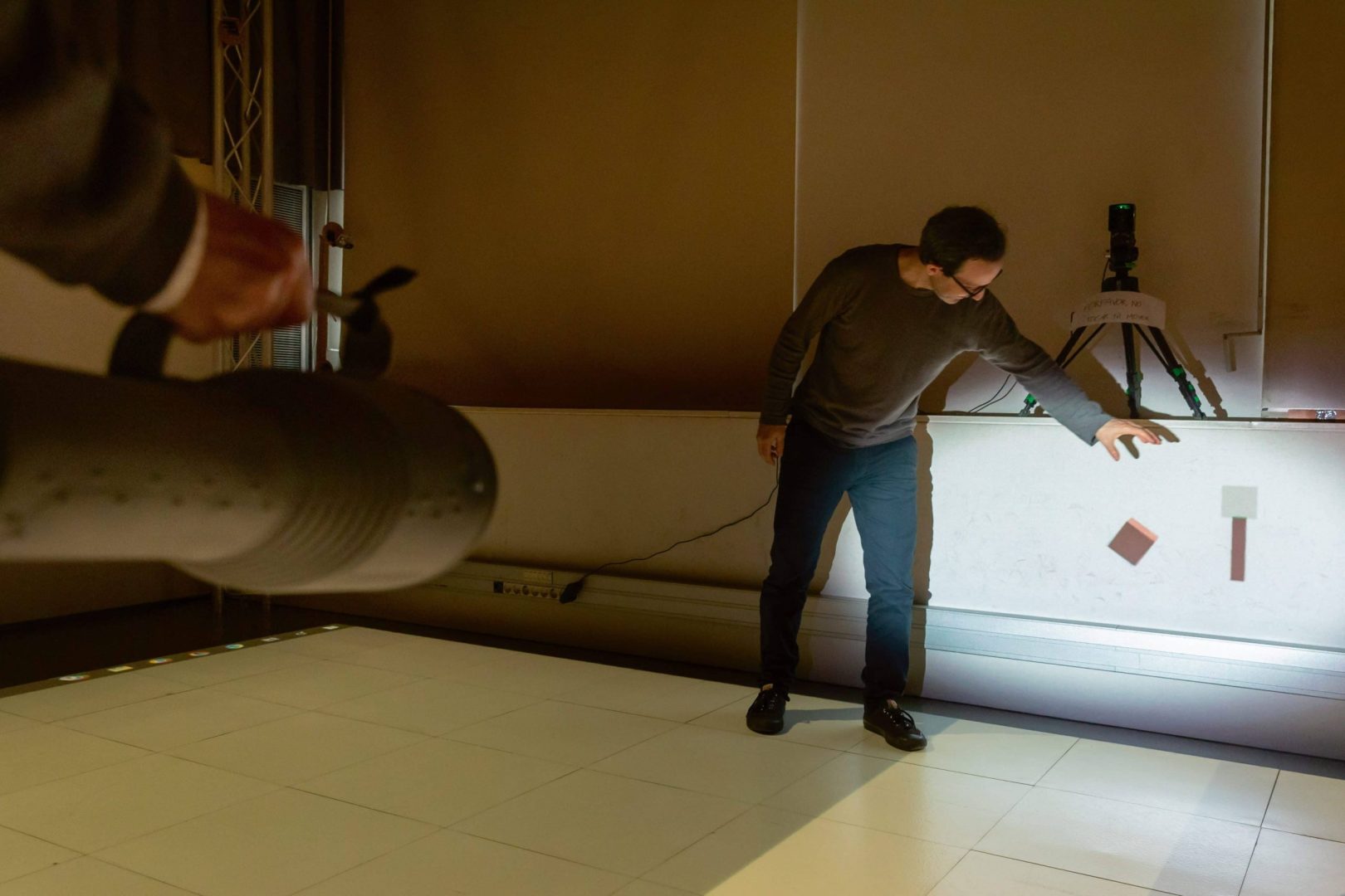 a man pointing at colored tiles on a wall digital production A man pointing at colored tiles on a wall.
