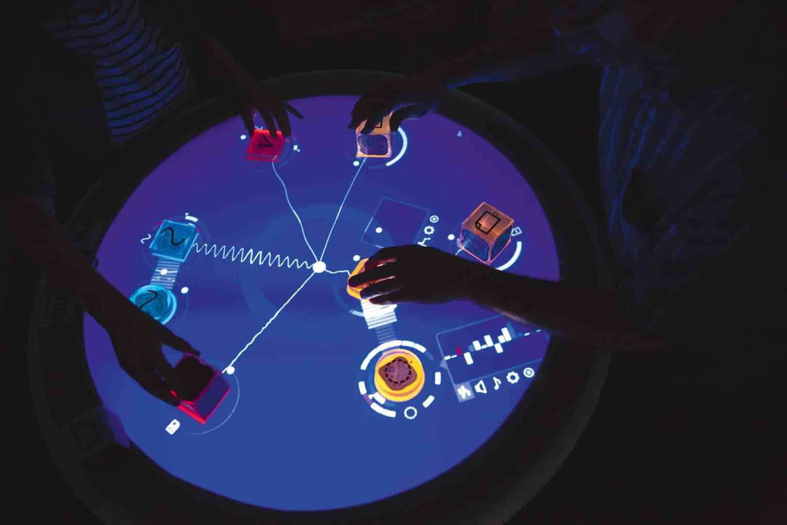 hands interacting with a digital touchscreen table displaying colorful shapes and graphics digital production Hands interacting with a digital touchscreen table displaying colorful shapes and graphics.