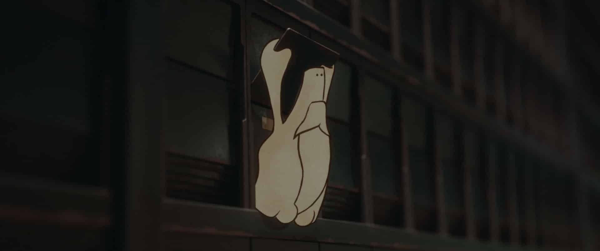 a closeup of a decorative sign hanging on a building depicting two hands forming a gesture the background consists of dark architectural elements adding contrast to the lighter sign digital production A close-up of a decorative sign hanging on a building, depicting two hands forming a gesture. The background consists of dark architectural elements, adding contrast to the lighter sign.