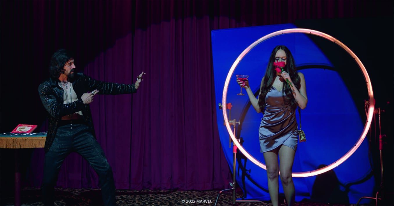 a man and woman performing on a stage with a circular light backdrop digital production A man and woman performing on a stage with a circular light backdrop.