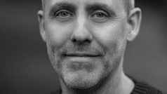 a man smiling in a dark sweater outdoors digital production A man smiling in a dark sweater, outdoors