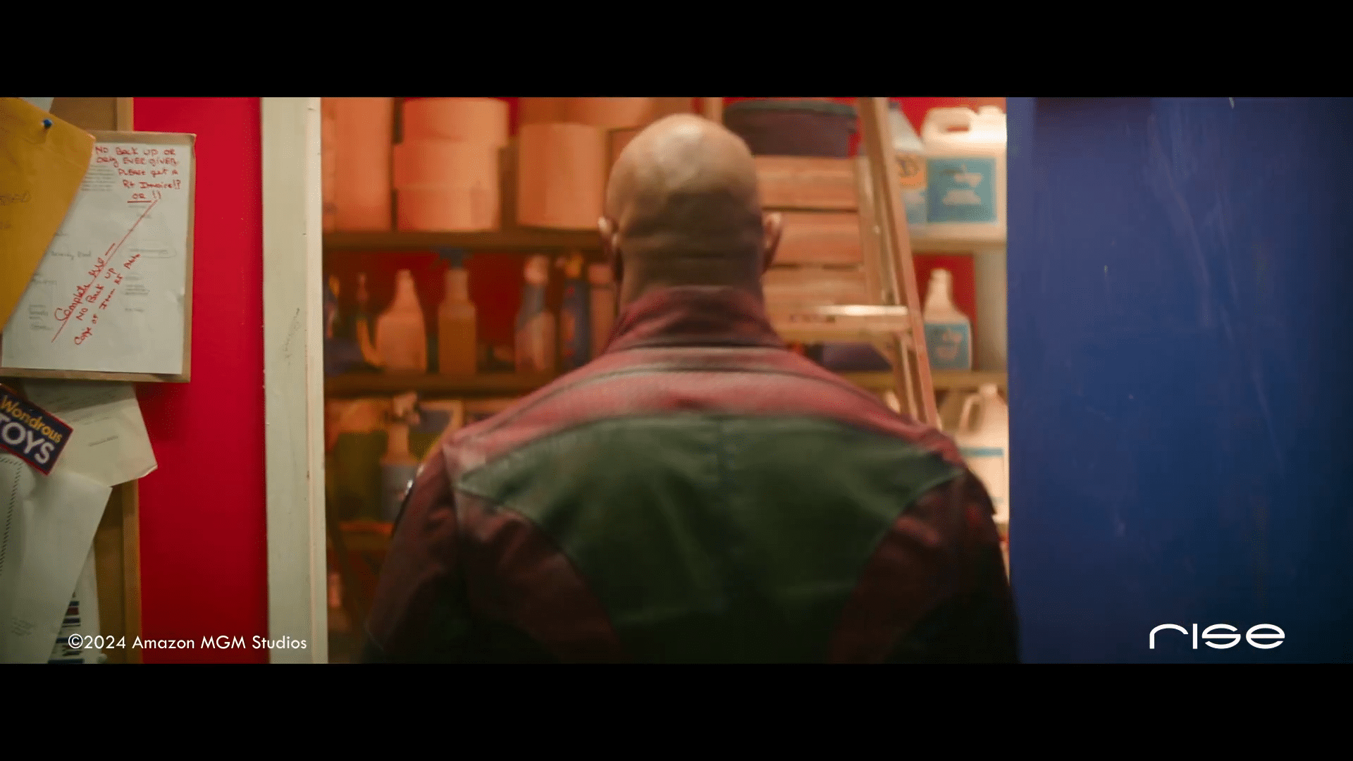 a man standing in front of a colorful storage room facing away digital production A man standing in front of a colorful storage room, facing away.