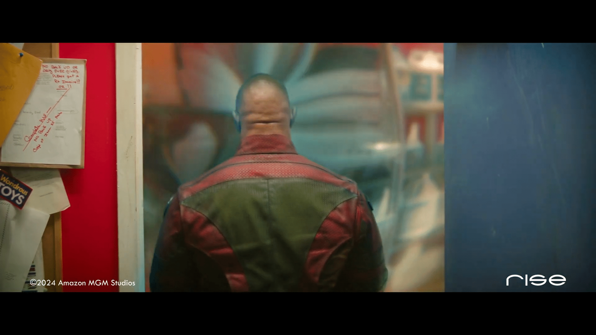 a persons back wearing a red and green jacket facing a colorful wall digital production A person's back wearing a red and green jacket facing a colorful wall