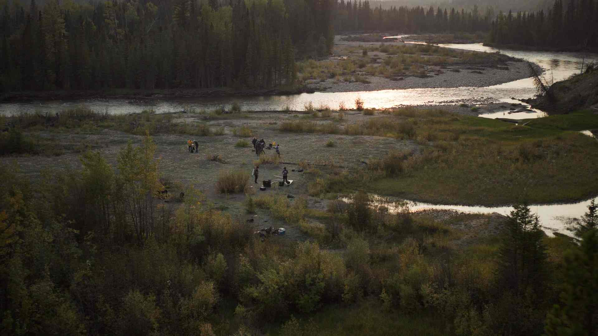 a scenic view of a river winding through a lush green landscape with groups of people gathered on the riverbank engaged in activities sunlight glimmers on the water creating a tranquil outdoor scene surrounded by trees digital production A scenic view of a river winding through a lush green landscape with groups of people gathered on the riverbank, engaged in activities. Sunlight glimmers on the water, creating a tranquil outdoor scene surrounded by trees.