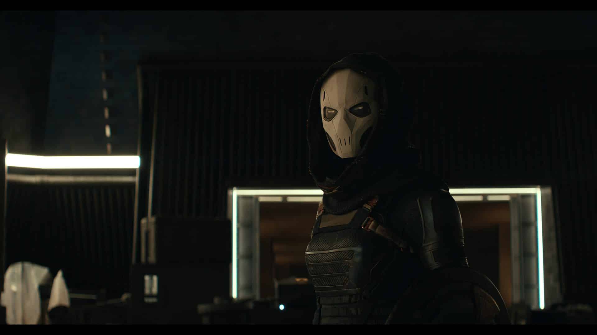 a masked character wearing a dark hooded outfit stands in a dimly lit room with a sleek modern design the characters mask features a skull design adding to the mysterious atmosphere digital production A masked character wearing a dark hooded outfit stands in a dimly lit room with a sleek, modern design. The character's mask features a skull design, adding to the mysterious atmosphere.