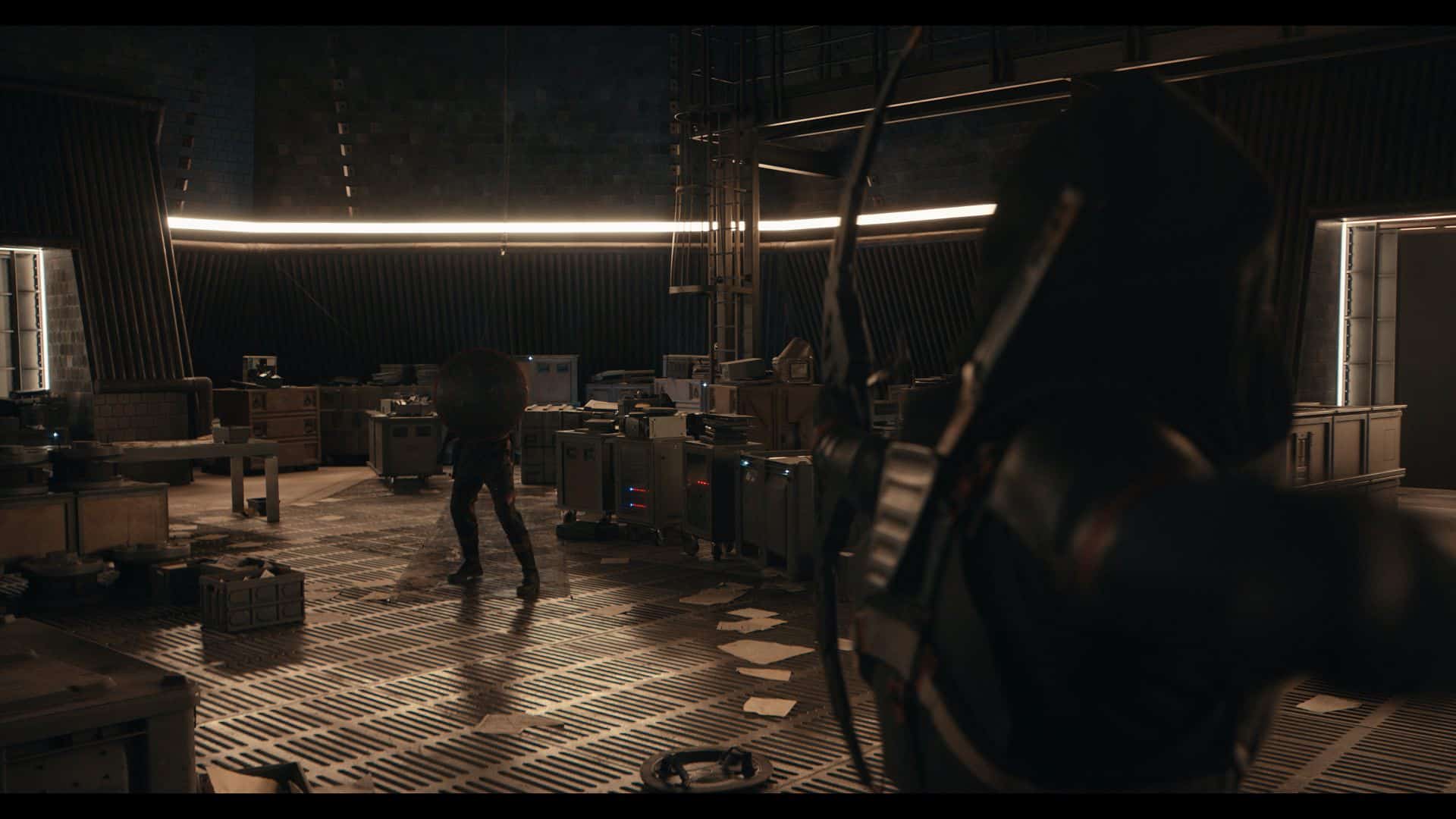 A dimly lit futuristic room filled with various equipment and crates. In the foreground, a figure with a bow is aiming at a person in motion, captured in a tense moment. The walls have a modern industrial design, illuminated by soft lighting.