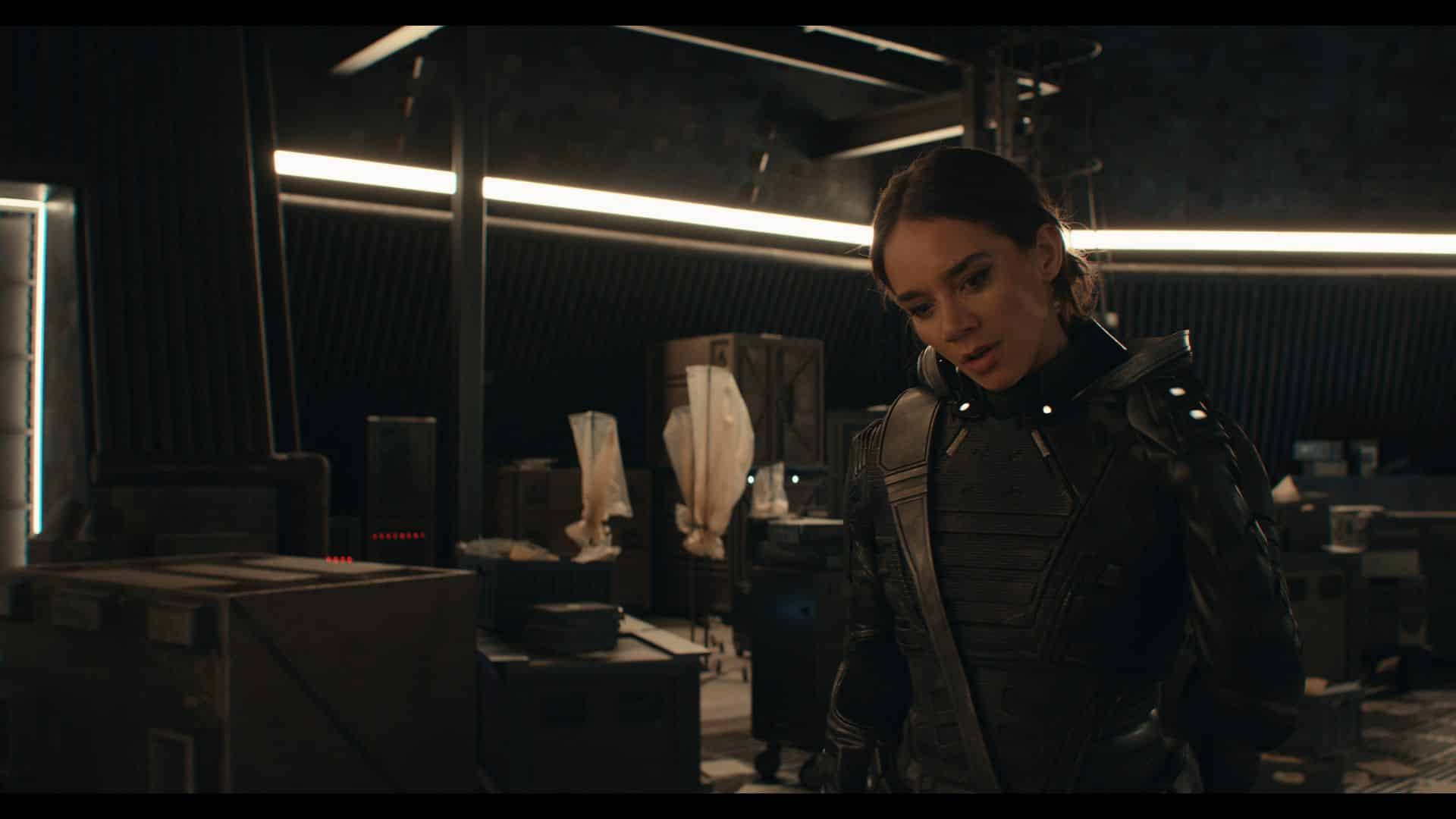 a woman wearing a futuristic metallic suit stands in a dimly lit hightech room filled with various equipment and containers she is looking down thoughtfully surrounded by a blend of dark and illuminated surfaces digital production A woman wearing a futuristic metallic suit stands in a dimly lit, high-tech room filled with various equipment and containers. She is looking down thoughtfully, surrounded by a blend of dark and illuminated surfaces.