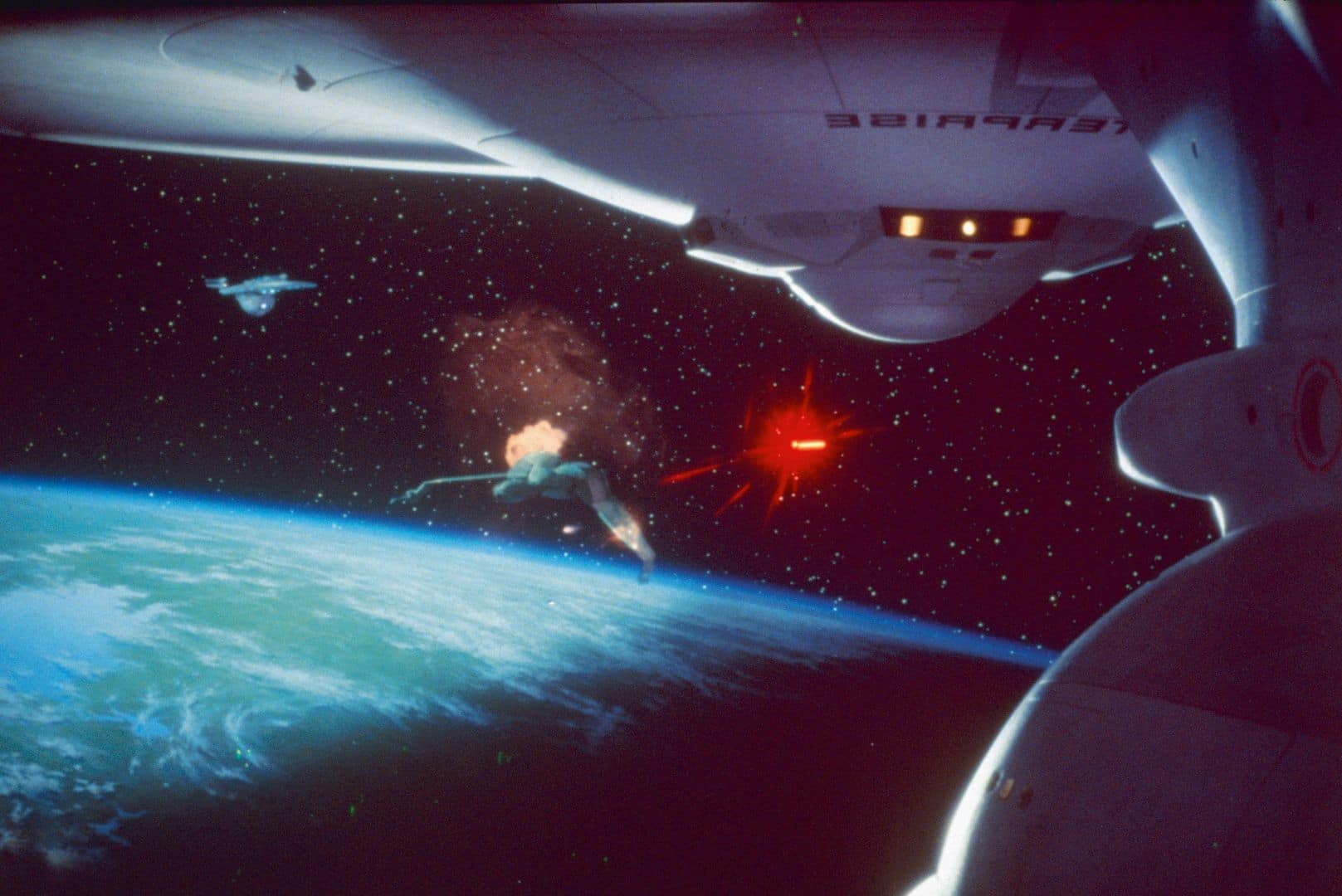 a spacecraft in orbit around earth with a distant view of another ship and a glowing red object the blue and green hues of the earth are visible beneath set against a starry black background digital production A spacecraft in orbit around Earth with a distant view of another ship and a glowing red object. The blue and green hues of the Earth are visible beneath, set against a starry black background.