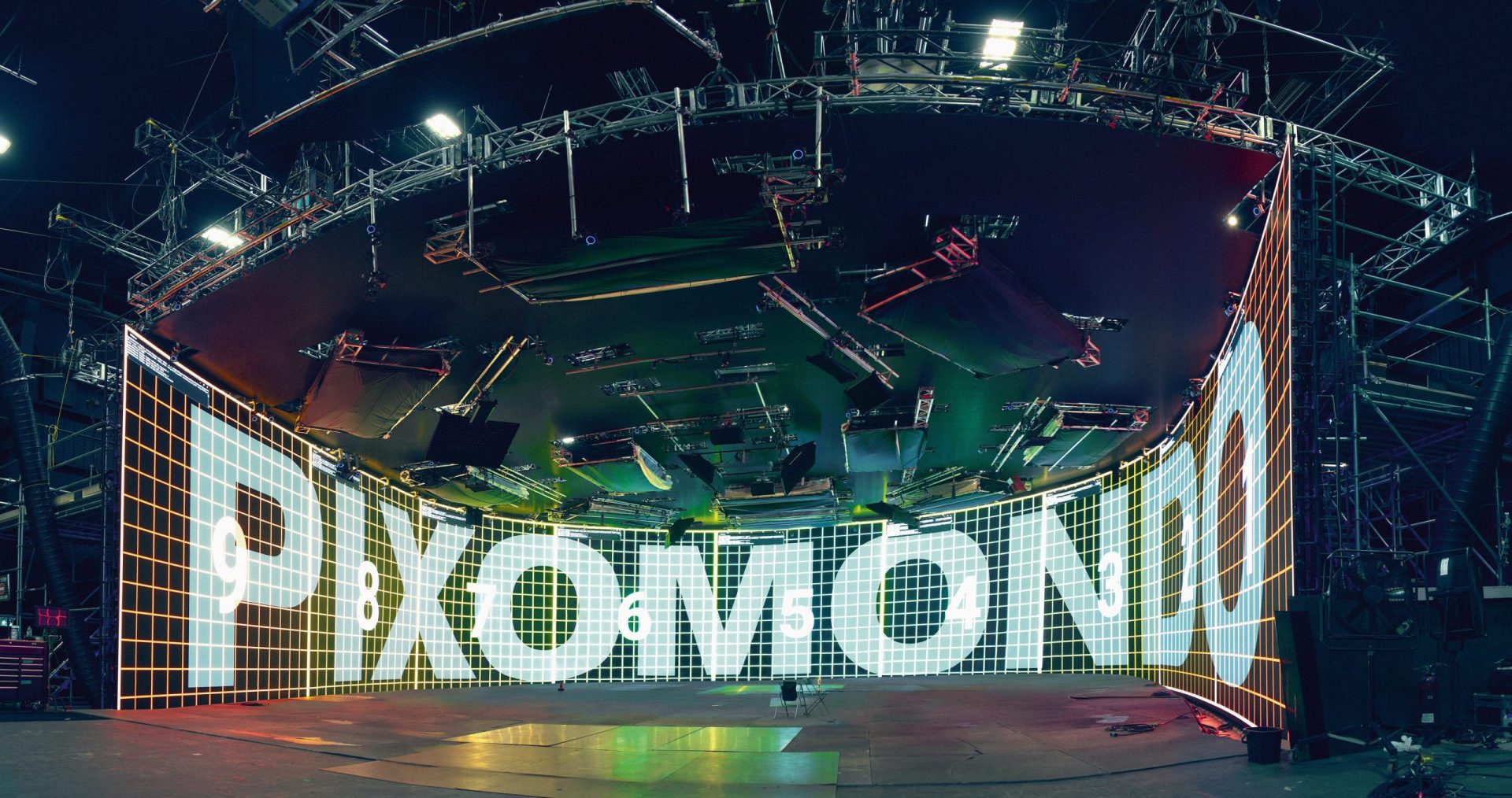 a large curved digital display in a hightech studio environment with the word pixomondo prominently featured in bold white letters against a colorful grid background digital production A large, curved digital display in a high-tech studio environment with the word 'PIXOMONDO' prominently featured in bold, white letters against a colorful grid background.