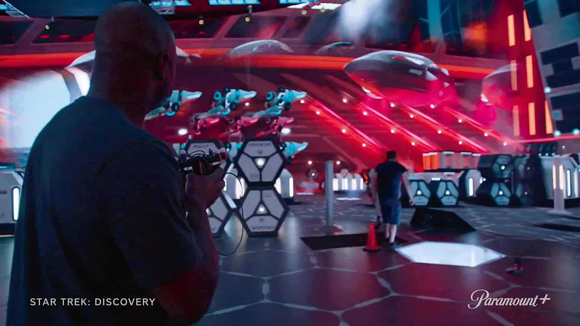 a character holding a futuristic device in a vibrant hightech space environment illuminated in red and blue lights background features hovering spacecraft and geometric structures the scene conveys an adventurous atmosphere typical of a scifi setting digital production A character holding a futuristic device in a vibrant, high-tech space environment, illuminated in red and blue lights. Background features hovering spacecraft and geometric structures. The scene conveys an adventurous atmosphere, typical of a sci-fi setting.