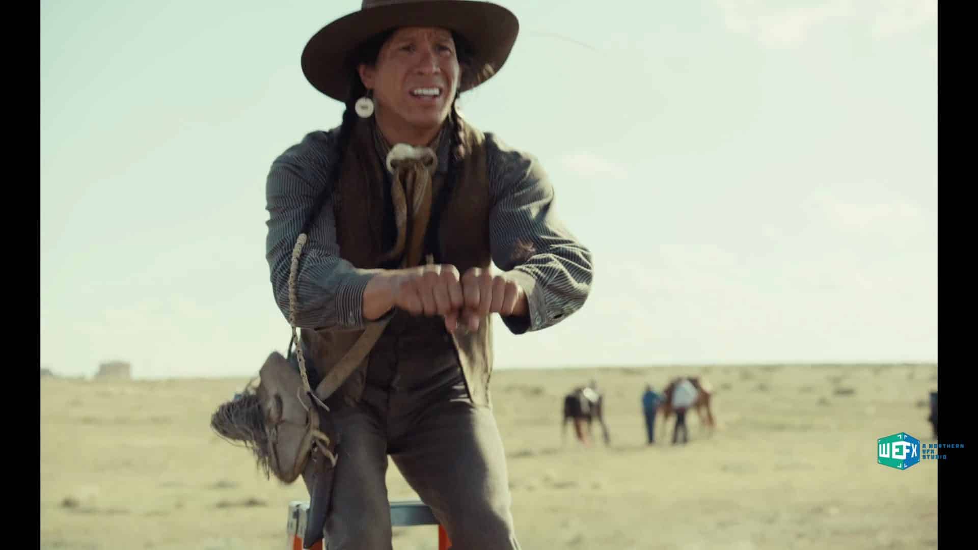 a man wearing a widebrimmed hat and traditional clothing rides a horse in an open field smiling and holding the reins a group of people and horses are visible in the background the sky is clear and blue digital production A man wearing a wide-brimmed hat and traditional clothing rides a horse in an open field, smiling and holding the reins. A group of people and horses are visible in the background. The sky is clear and blue.