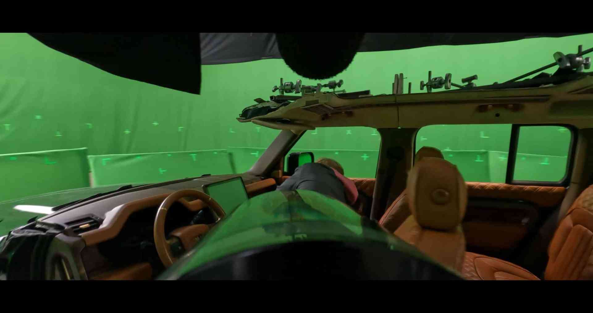 interior of a film production vehicle equipped with cameras and green screen elements the dashboard features a digital display while the seats are upholstered in brown leather green backdrop suggests a scene setting for visual effects digital production Interior of a vehicle on a set with green screen background, showing crew member working and camera equipment.