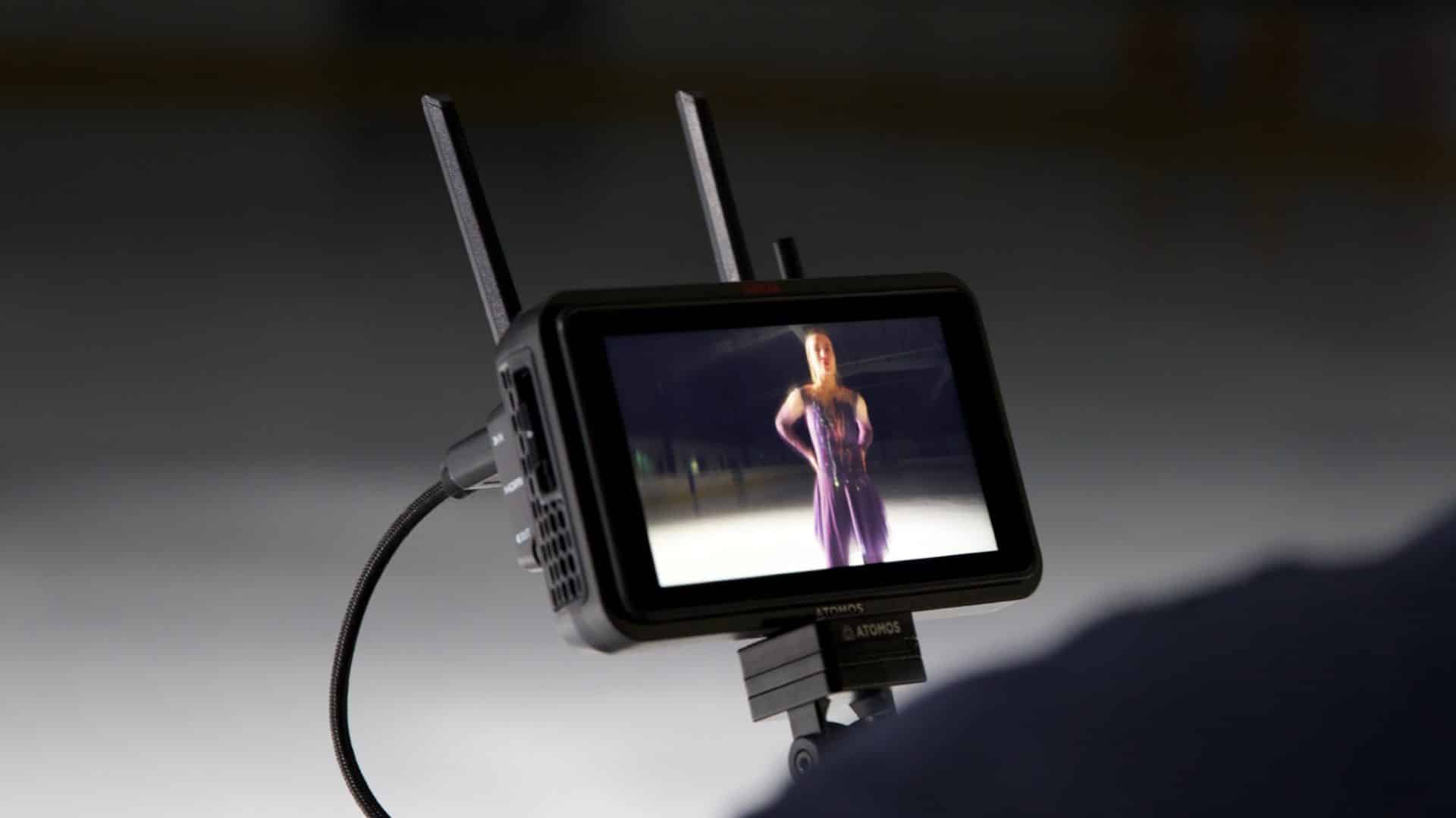 a monitor displaying a female ice skater in a purple costume with antennas visible on its sides the background features an ice rink suggesting a performance or rehearsal setting digital production A monitor displaying a female ice skater in a purple costume, with antennas visible on its sides. The background features an ice rink, suggesting a performance or rehearsal setting.