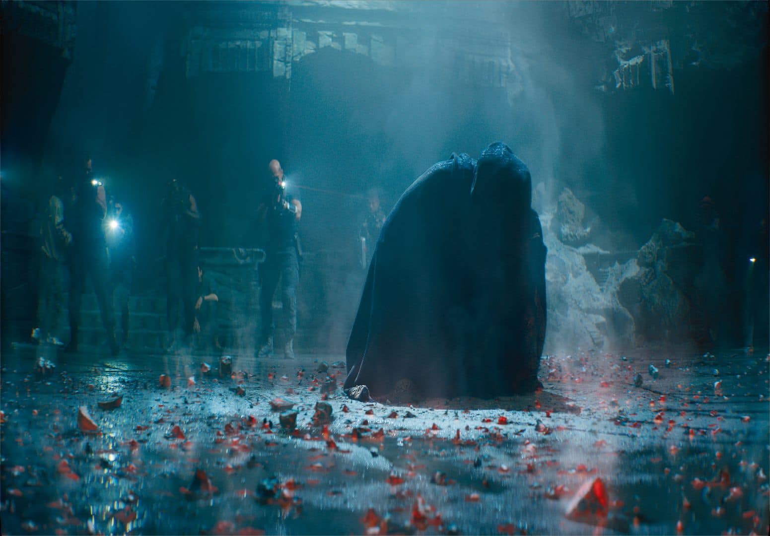 a dark figure in a cloak kneels on a wet debrisstrewn floor surrounded by people holding flashlights in a dimly lit environment smoke and mist create an atmospheric effect digital production A dark figure in a cloak kneels on a wet, debris-strewn floor surrounded by people holding flashlights in a dimly lit environment. Smoke and mist create an atmospheric effect.