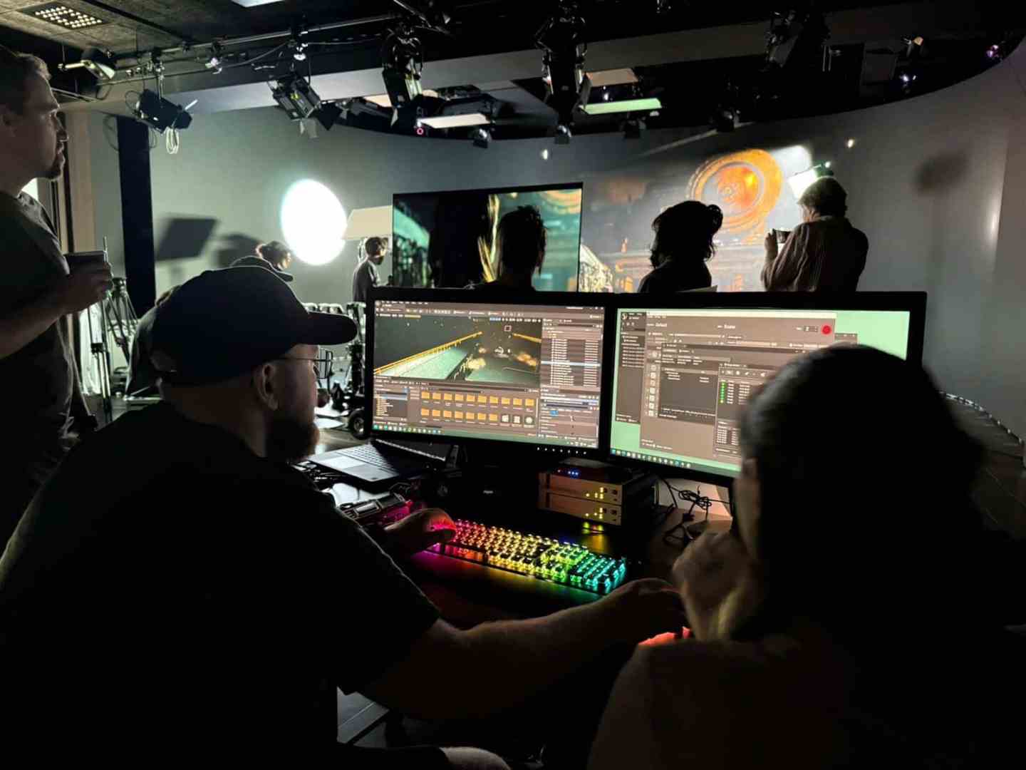 a team of creative professionals collaborating in a studio with one person focused on editing on dual computer screens displaying video editing software ambient lighting enhances the hightech environment digital production A team of creative professionals collaborating in a studio, with one person focused on editing on dual computer screens displaying video editing software. Ambient lighting enhances the high-tech environment.