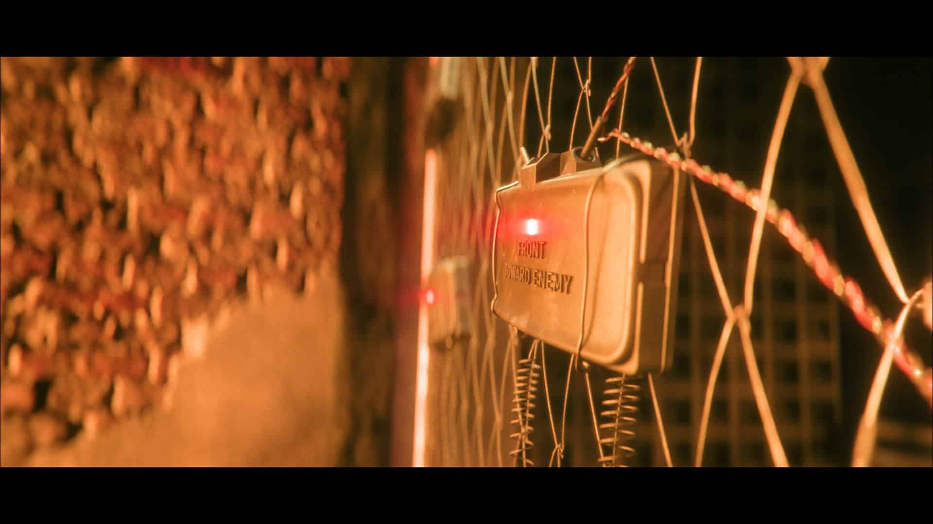 a closeup view of a security alarm system attached to a fence with red indicator lights visible the background shows a wall made of stones digital production A close-up view of a security alarm system attached to a fence, with red indicator lights visible. The background shows a wall made of stones.