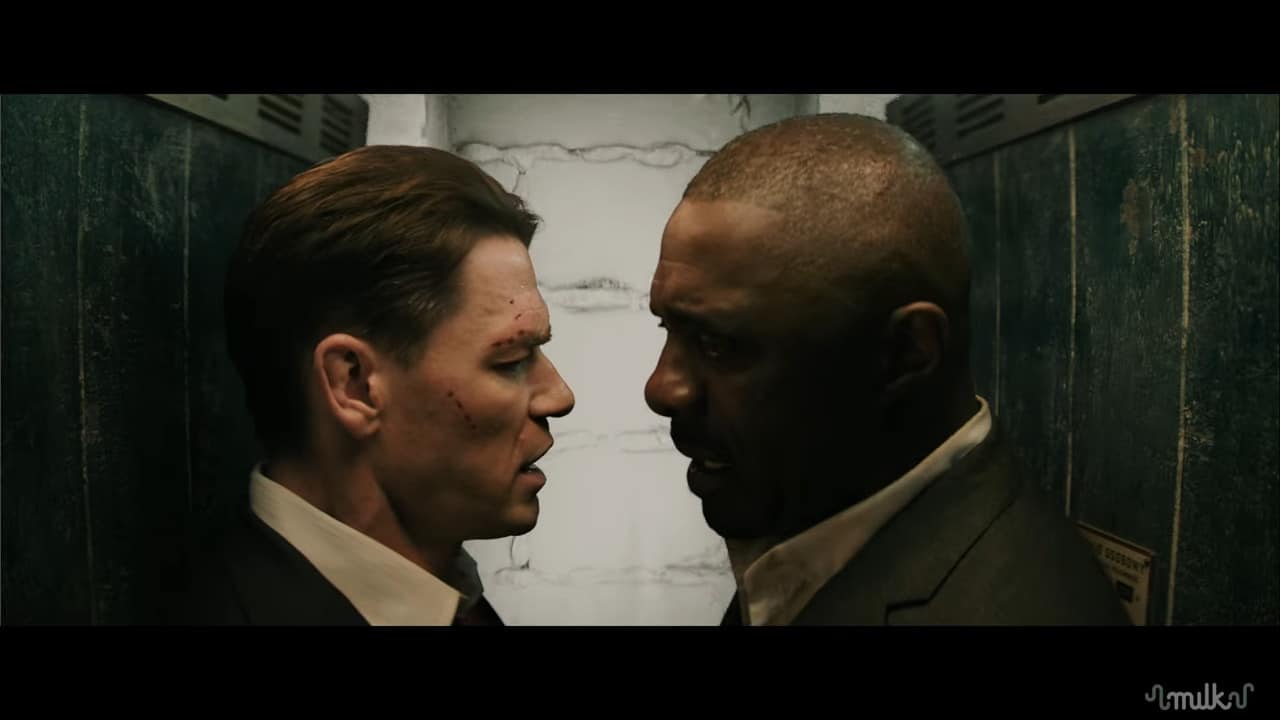 two men facing each other in a confined space possibly an elevator one man has visible bruises on his face while both are dressed in dark suits the background shows blurred outlines of metal walls and overhead lights digital production Two men facing each other in a confined space, possibly an elevator. One man has visible bruises on his face, while both are dressed in dark suits. The background shows blurred outlines of metal walls and overhead lights.