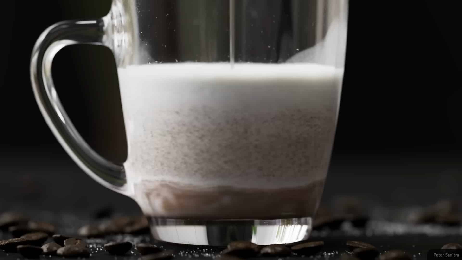 a closeup of a clear glass mug with layers of chocolate and milk mixing together dark coffee beans and sugar are scattered on a dark surface around the mug digital production A close-up of a clear glass mug with layers of chocolate and milk mixing together. Dark coffee beans and sugar are scattered on a dark surface around the mug.