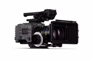 A professional cinema camera from Sony, featuring a large lens, a matte box, and control buttons on the side. The camera is mounted on a support rig for stability.