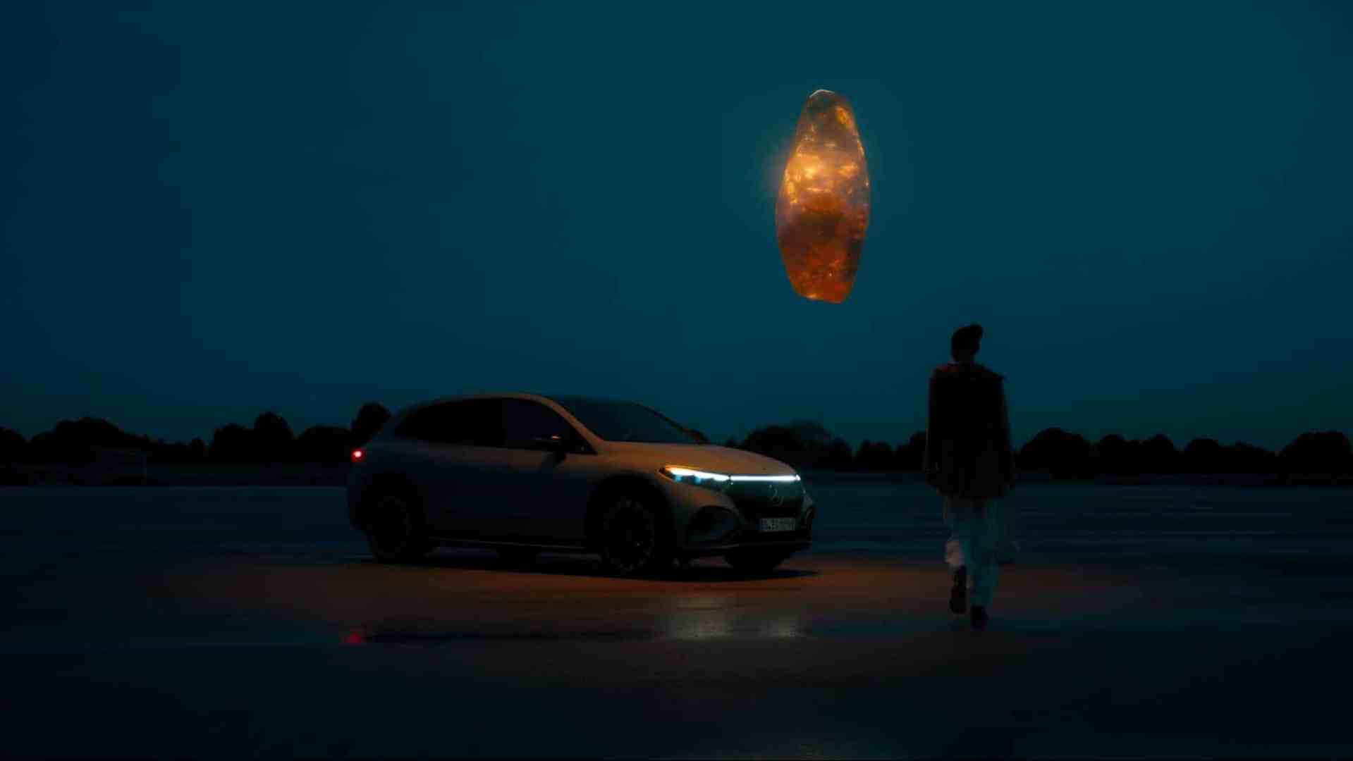 a person walking towards a car parked on a dark illuminated surface above the car there is a glowing ovalshaped object in the sky the scene is set during twilight with a blue tone digital production A person walking towards a car parked on a dark, illuminated surface. Above the car, there is a glowing, oval-shaped object in the sky. The scene is set during twilight with a blue tone.