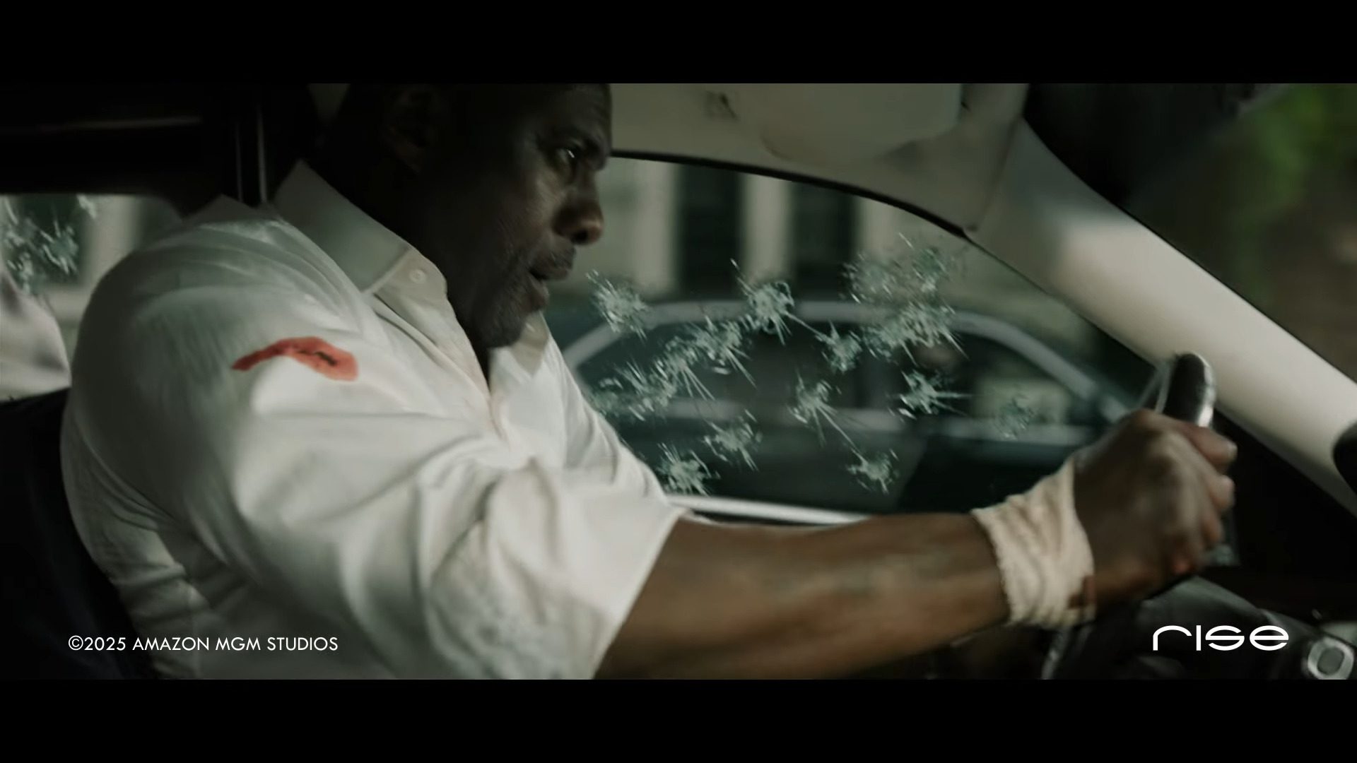 a man gripping the steering wheel of a car focused and distressed with a bloodstained shirt and bandaged hand the vehicles windshield shows bullet holes reflecting evidence of a violent altercation digital production A man gripping the steering wheel of a car, focused and distressed, with a blood-stained shirt and bandaged hand. The vehicle's windshield shows bullet holes, reflecting evidence of a violent altercation.