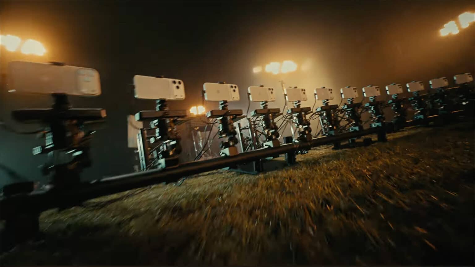 a row of smartphones mounted on mechanical rigs lined up in a dimly lit environment with multiple spotlights illuminating the scene creating a dramatic atmosphere digital production A row of smartphones mounted on mechanical rigs, lined up in a dimly lit environment with multiple spotlights illuminating the scene, creating a dramatic atmosphere.