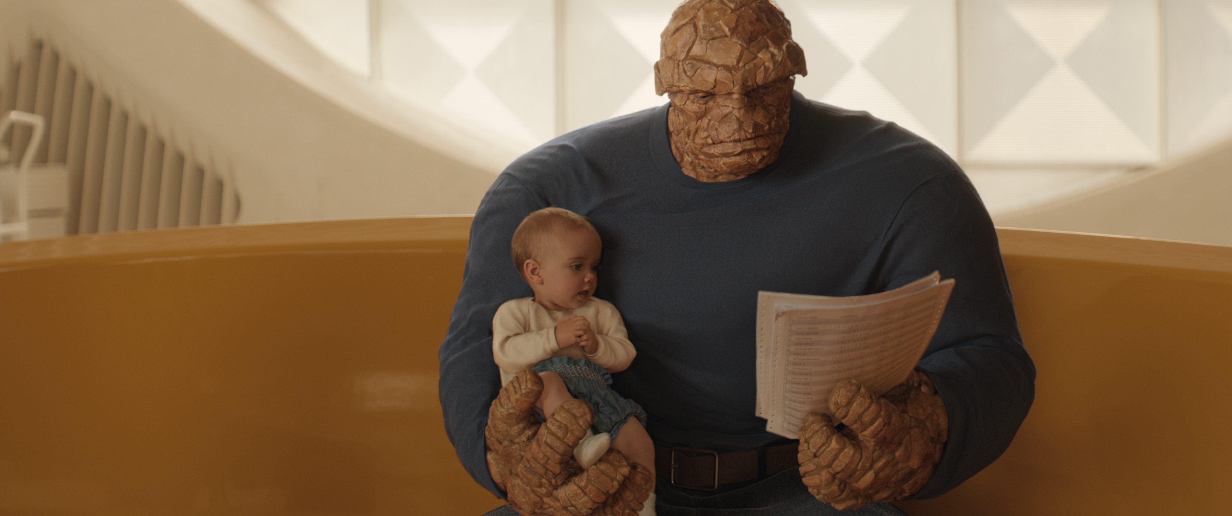 a large rocky superhero holding a baby on his lap while reading from a sheet of paper they are sitting together in a spacious brightly lit room with modern decor digital production A large, rocky superhero holding a baby on his lap while reading from a sheet of paper. They are sitting together in a spacious, brightly lit room with modern decor.