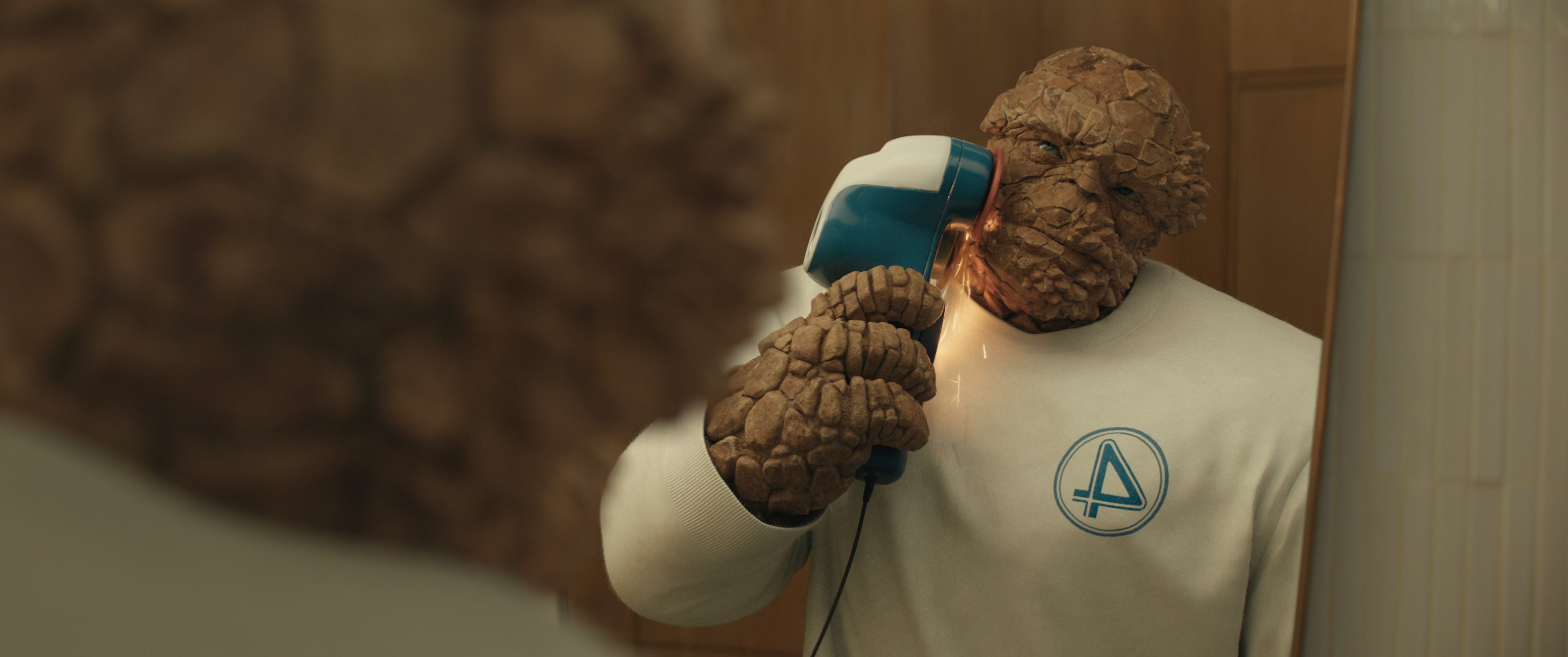 a character with a rocky texture resembling a superhero stands in front of a mirror using an ear cleaner he wears a white shirt with a blue emblem and the bathroom is warmly lit digital production A character with a rocky texture, resembling a superhero, stands in front of a mirror, using an ear cleaner. He wears a white shirt with a blue emblem, and the bathroom is warmly lit.