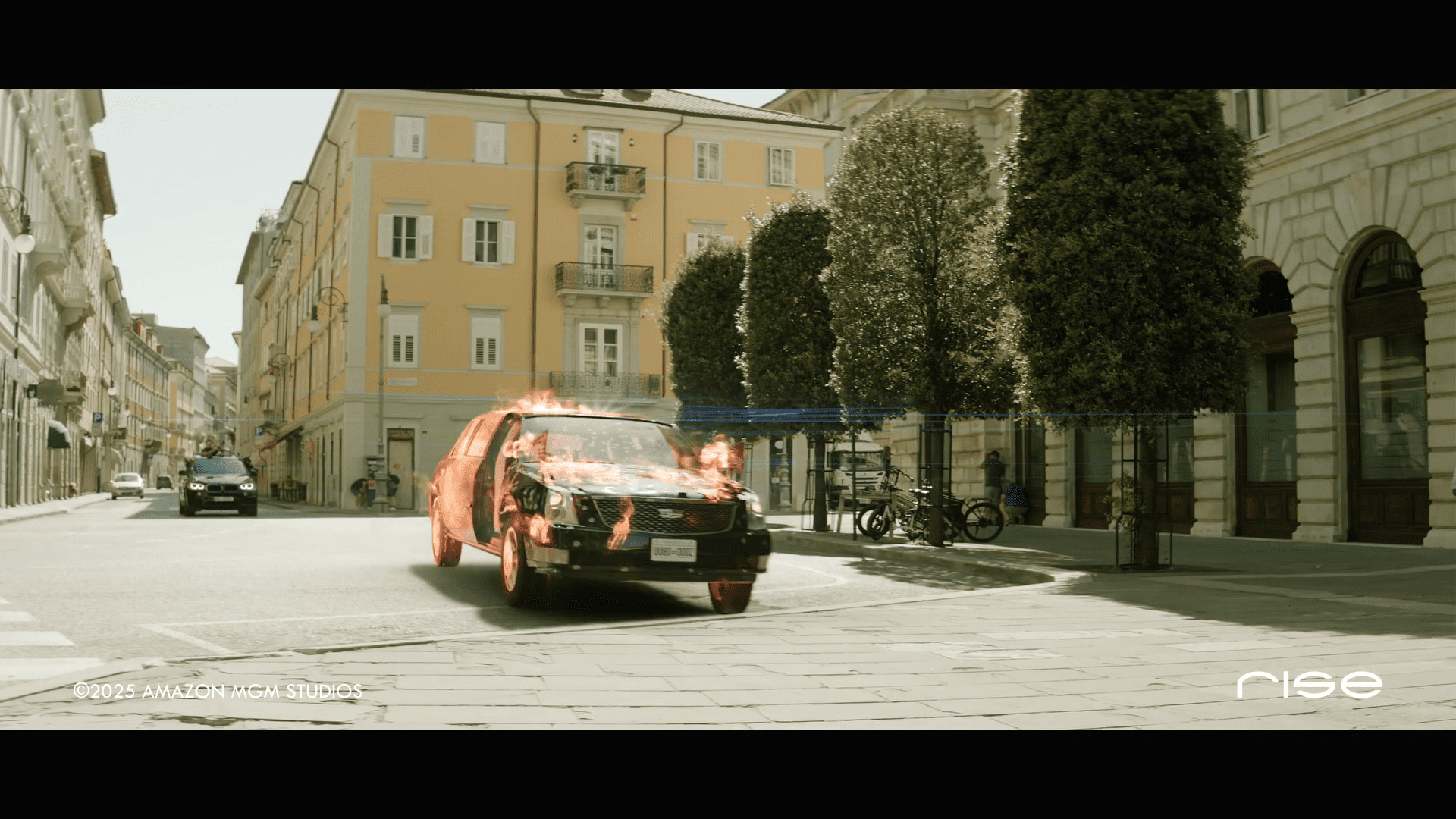 a black car is engulfed in flames on a deserted street surrounded by yellow buildings and neatly trimmed trees the area appears abandoned highlighting the dramatic scene with smoke billowing from the vehicle digital production A black car is engulfed in flames on a deserted street, surrounded by yellow buildings and neatly trimmed trees. The area appears abandoned, highlighting the dramatic scene, with smoke billowing from the vehicle.