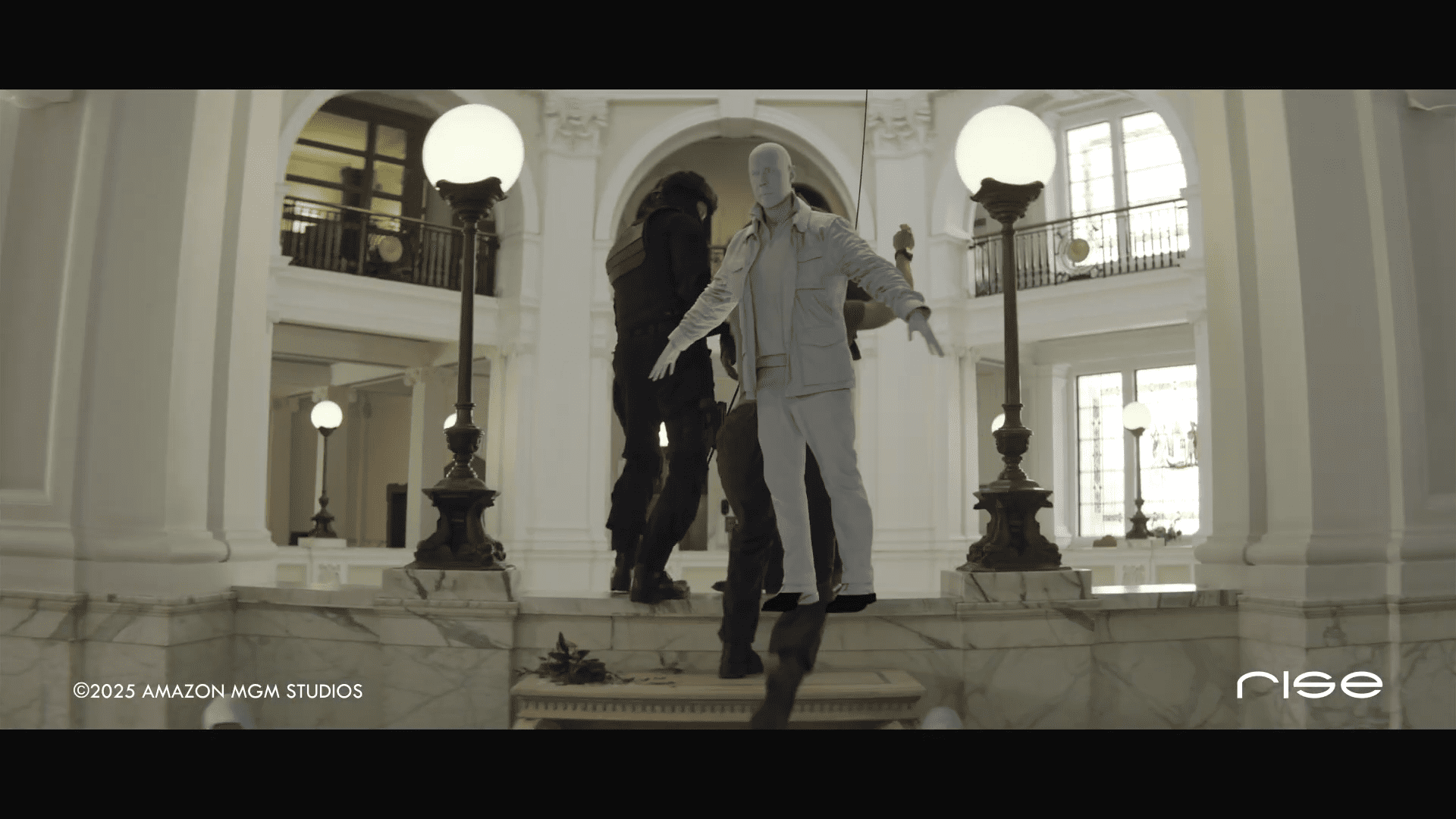 a stylized scene in a grand marblefloored atrium with large columns and decorative lighting a person in a white tracksuit appears to be levitating above a dark figure who is transitioning into a standing position digital production A stylized scene in a grand, marble-floored atrium with large columns and decorative lighting. A person in a white tracksuit appears to be levitating above a dark figure, who is transitioning into a standing position.
