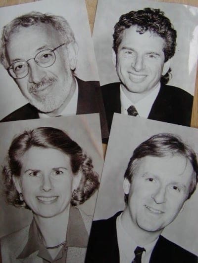 four black and white portraits of individuals the top left features a man with glasses and gray hair while the top right shows a man with curly hair in a suit the bottom left depicts a woman with shoulderlength hair and the bottom right presents a man with short hair in a dress shirt each person is smiling at the camera digital production Four black and white portraits of individuals. The top left features a man with glasses and gray hair, while the top right shows a man with curly hair in a suit. The bottom left depicts a woman with shoulder-length hair, and the bottom right presents a man with short hair in a dress shirt. Each person is smiling at the camera.