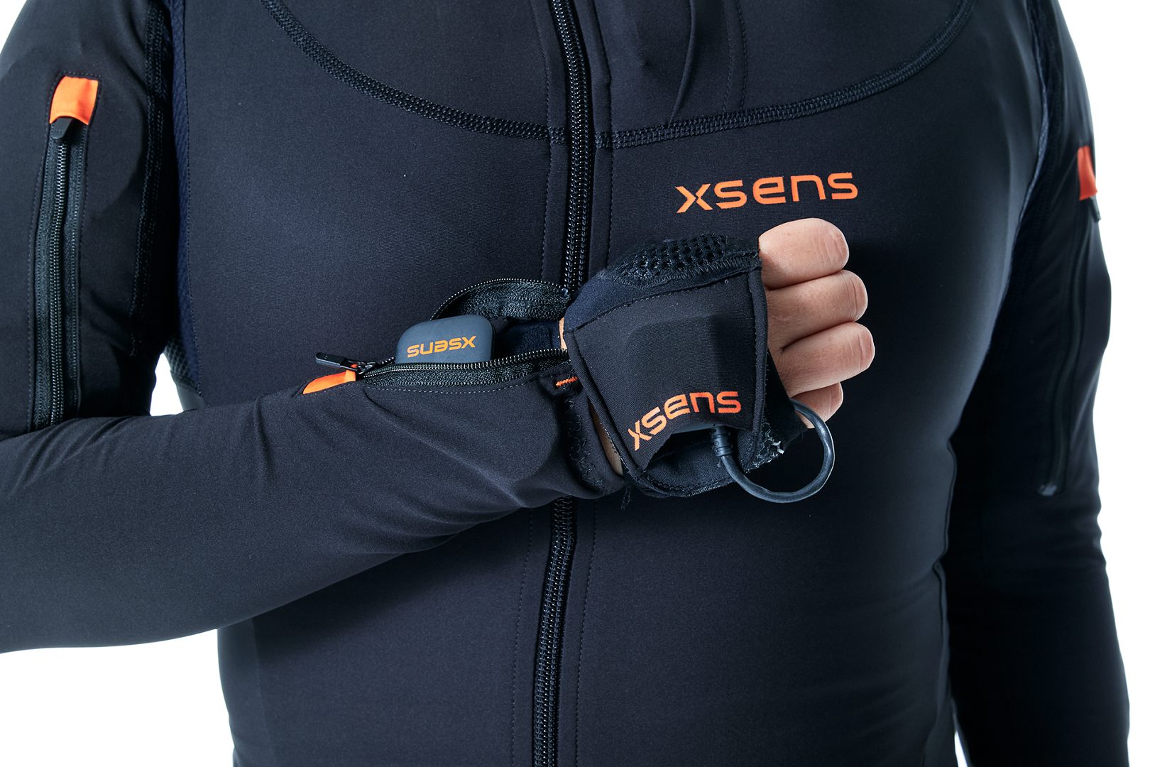 a closeup of a person wearing a black motion capture suit with orange accents the individual is adjusting a glove that is part of the suit showcasing the technology used for motion tracking digital production A close-up of a person wearing a black motion capture suit with orange accents. The individual is adjusting a glove that is part of the suit, showcasing the technology used for motion tracking.
