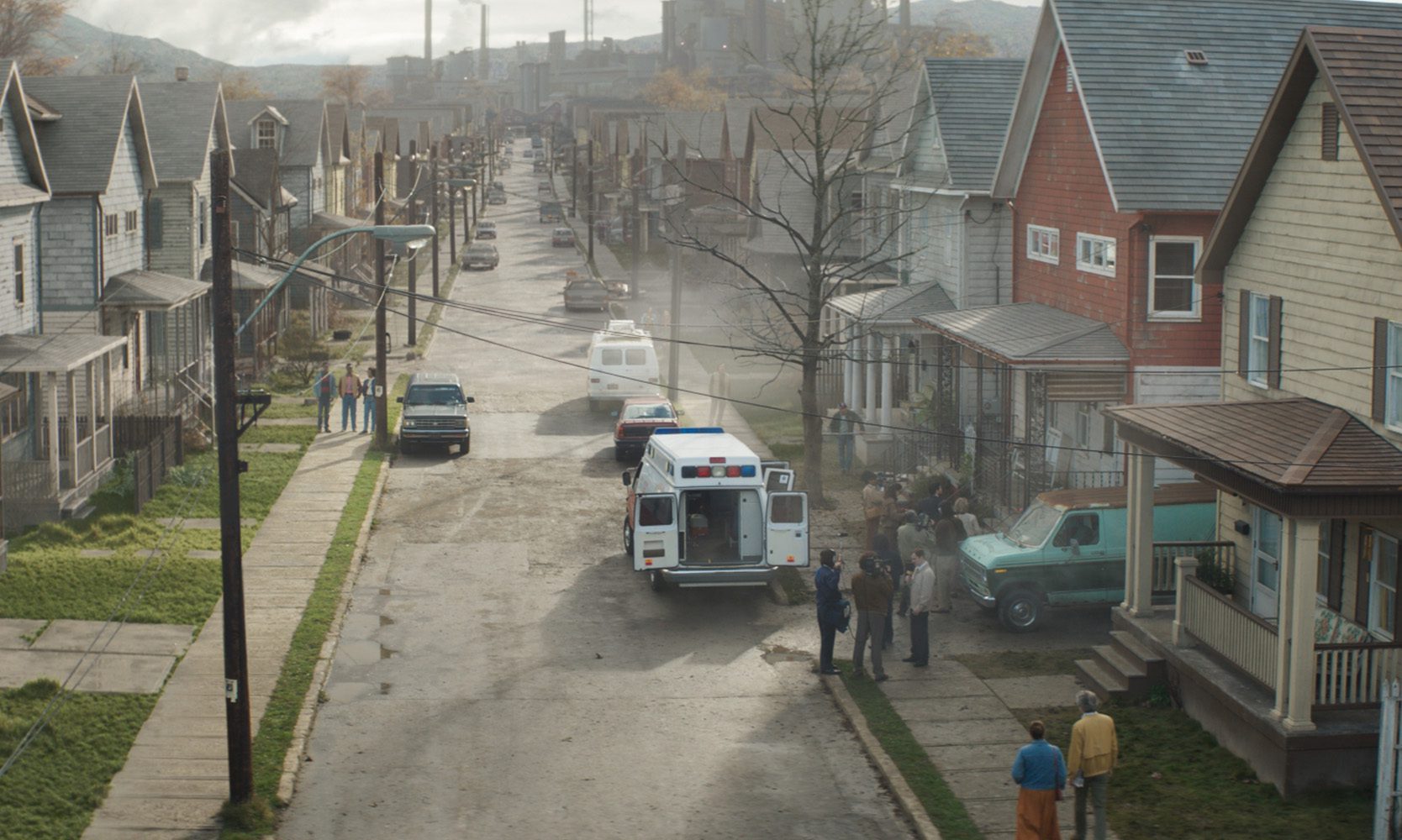 a quiet residential street lined with modest houses an ambulance parked with its doors open a few people gather near the ambulance while a couple of cars are parked along the road smoke rises in the background hinting at industrial activity digital production A quiet residential street lined with modest houses, an ambulance parked with its doors open. A few people gather near the ambulance, while a couple of cars are parked along the road. Smoke rises in the background, hinting at industrial activity.