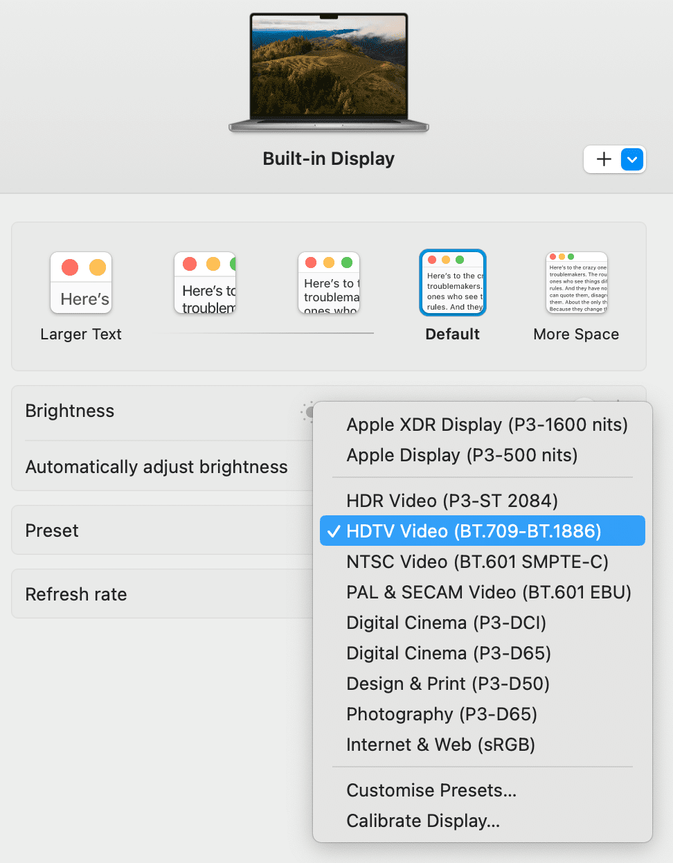 a laptop screen displaying system preferences for display settings the interface shows options for brightness text size and various display presets including hdtv video a serene landscape image is visible as the background digital production A laptop screen displaying system preferences for display settings. The interface shows options for brightness, text size, and various display presets, including 'HDTV Video.' A serene landscape image is visible as the background.