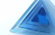 A series of transparent blue acrylic pyramids arranged with varying sizes, showcasing a smooth surface and reflecting light against a white background.