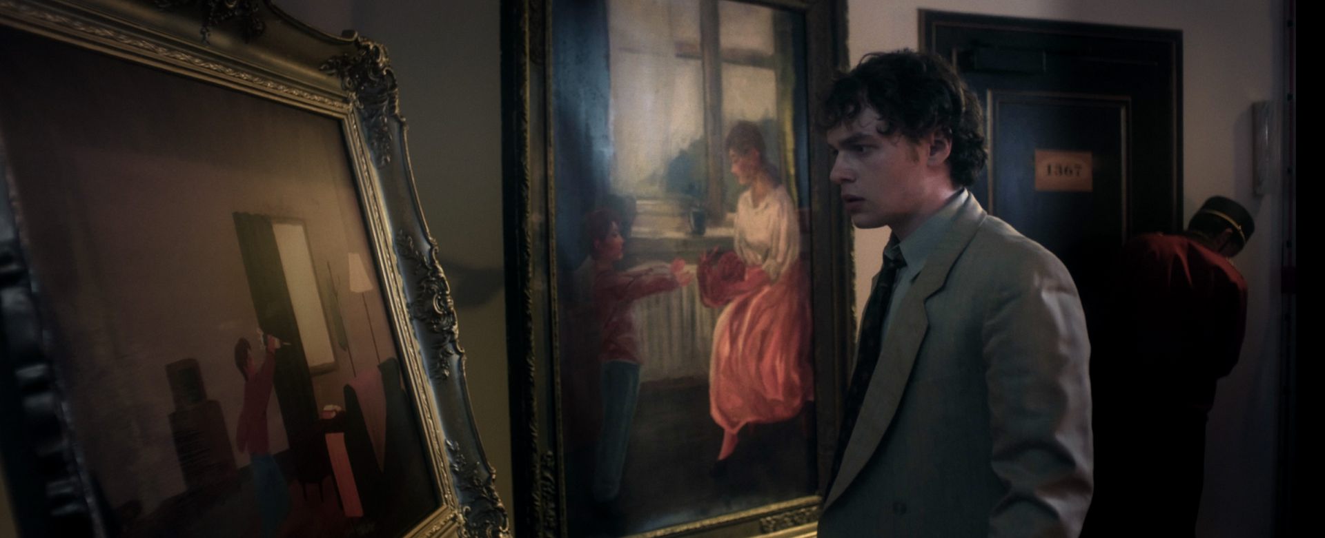 a man in a lightcolored suit stands contemplatively near two paintings in a dimly lit gallery one painting depicts a woman in a pink dress while the other features abstract figures a shadowy figure is partially visible in the background digital production A man in a light-colored suit stands contemplatively near two paintings in a dimly lit gallery. One painting depicts a woman in a pink dress, while the other features abstract figures. A shadowy figure is partially visible in the background.