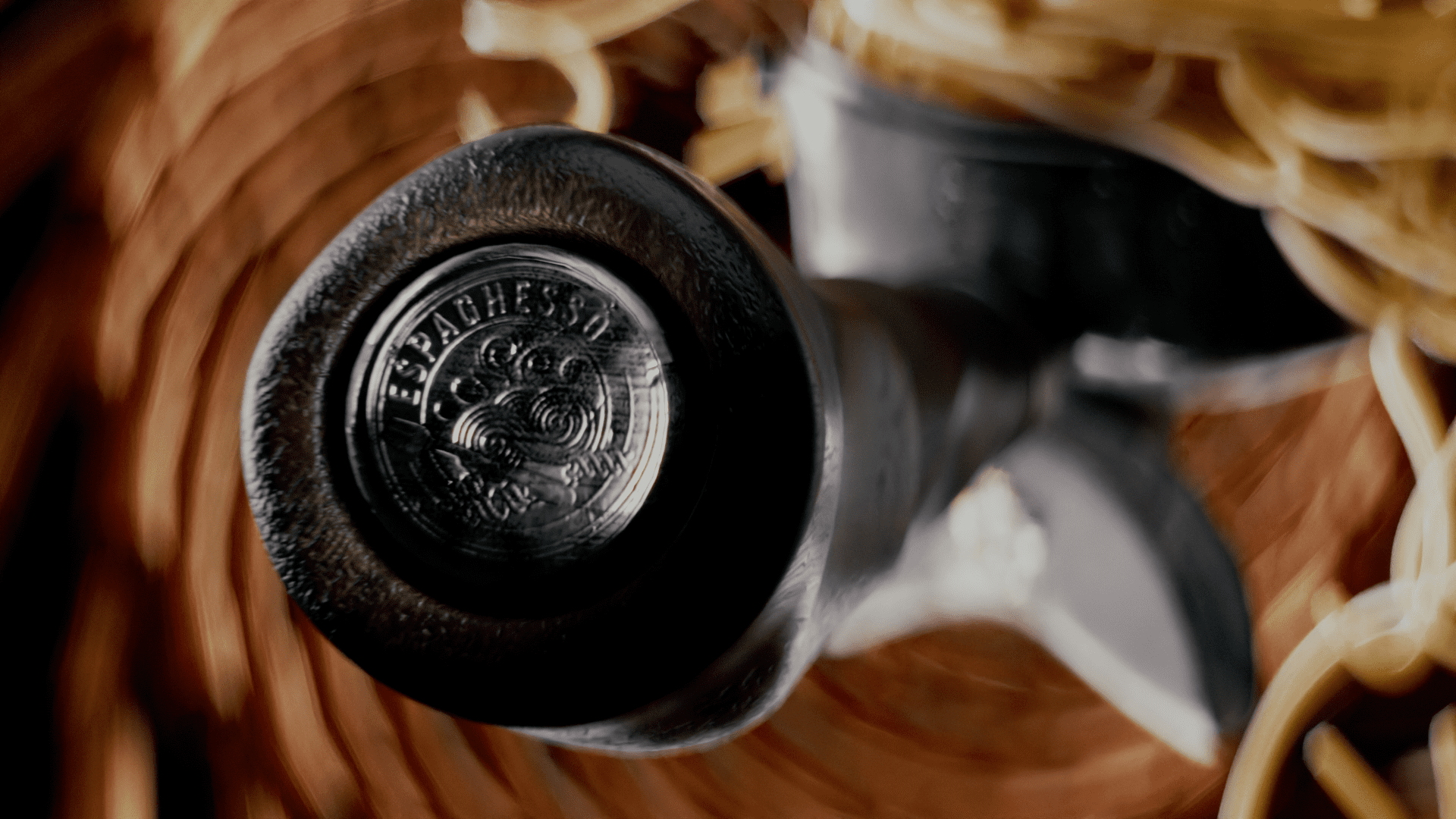 closeup of a vintage pasta makers handle featuring an embossed design set against a blurred background of woven materials and spaghetti the scene conveys a rustic culinary atmosphere digital production Close-up of a vintage pasta maker's handle, featuring an embossed design, set against a blurred background of woven materials and spaghetti. The scene conveys a rustic culinary atmosphere.